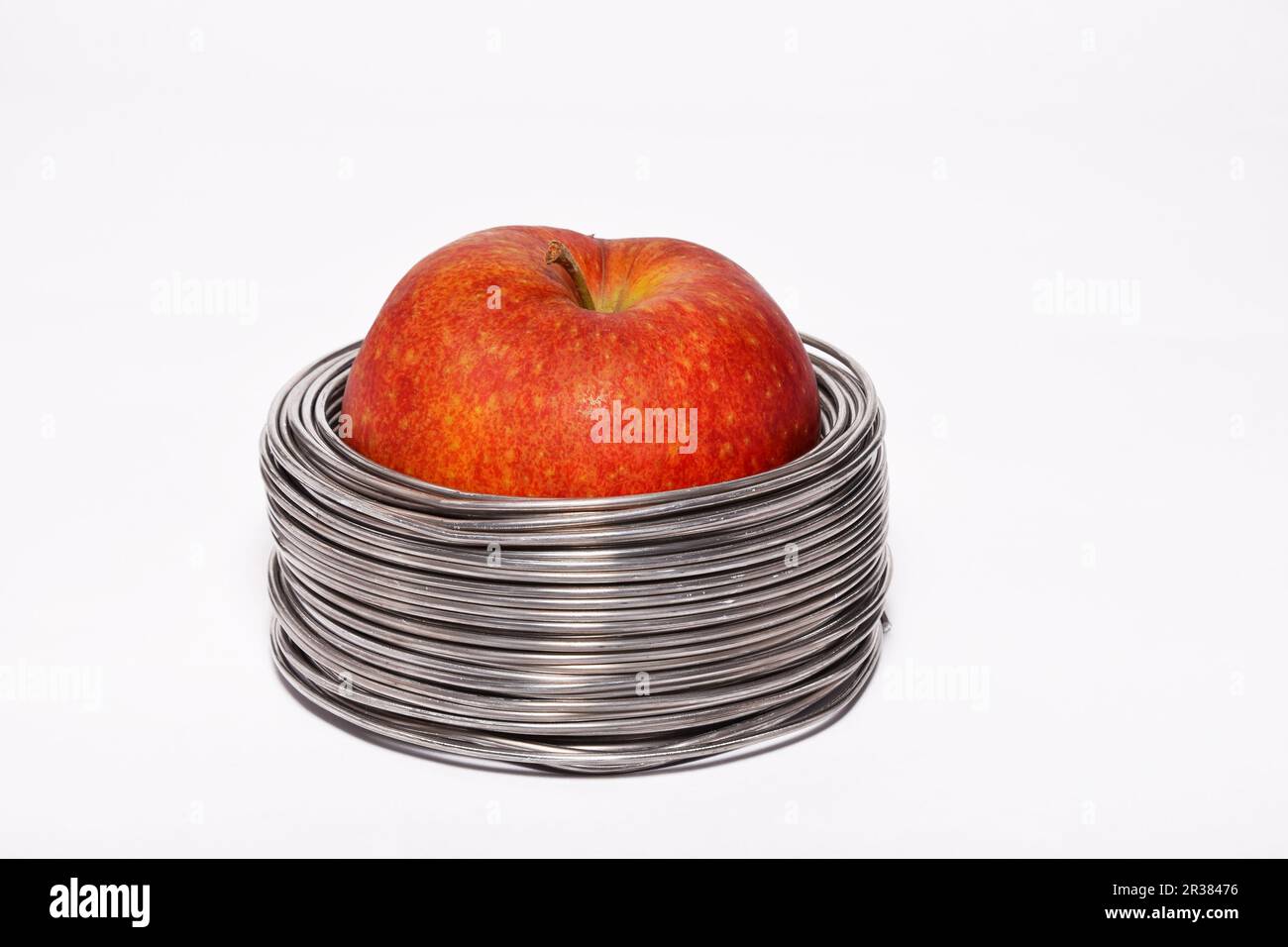 Apple filaire : ensemble pomme rouge dans des bobines de fil aluminium isolé sur fond blanc Banque D'Images