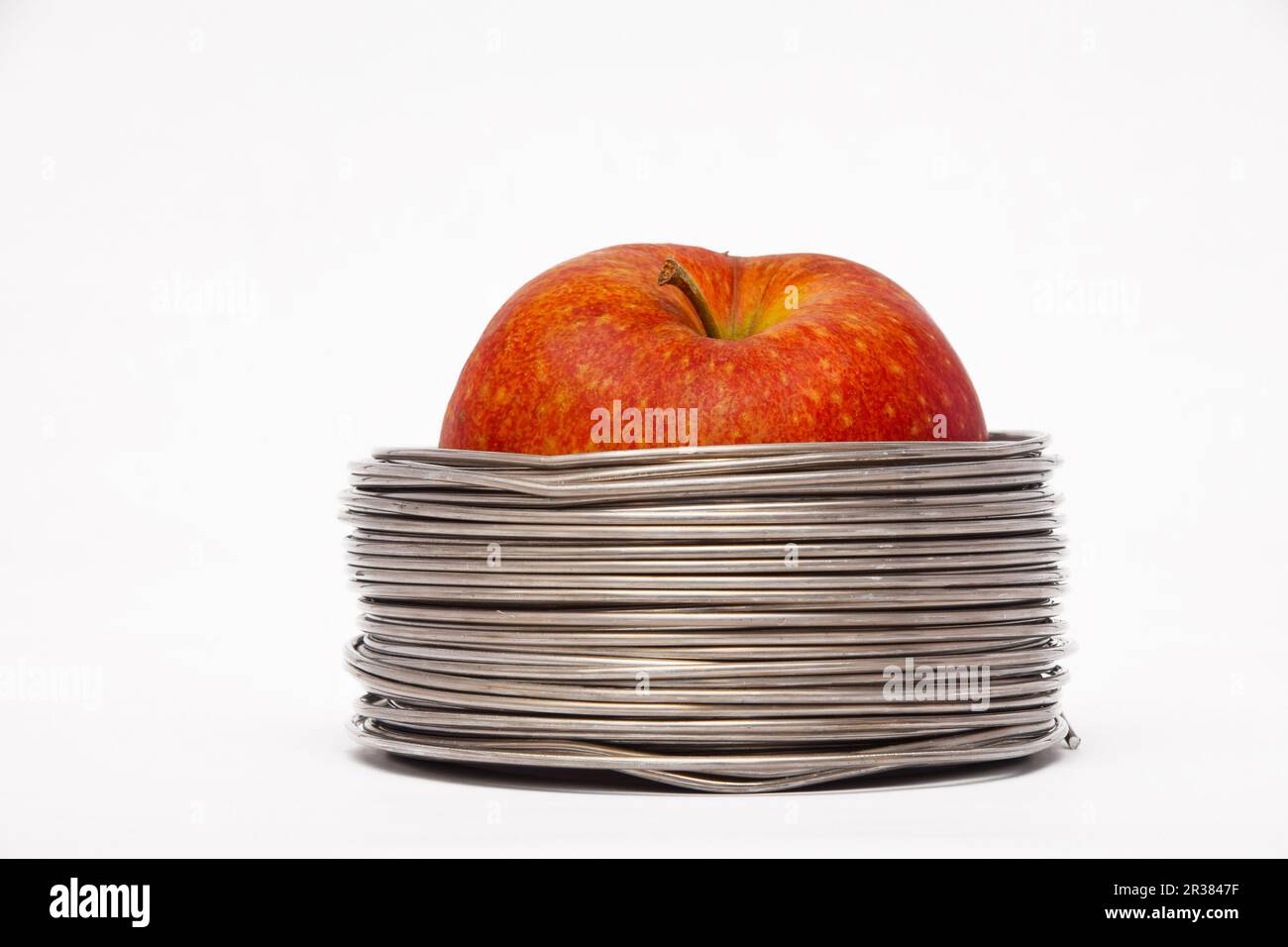 Apple filaire : ensemble pomme rouge dans des bobines de fil aluminium isolé sur fond blanc Banque D'Images