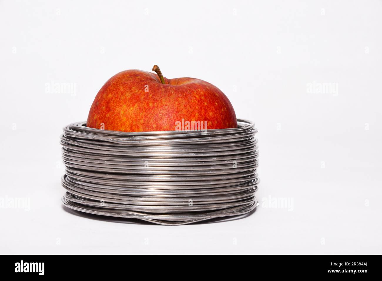 Apple filaire : ensemble pomme rouge dans des bobines de fil aluminium isolé sur fond blanc Banque D'Images