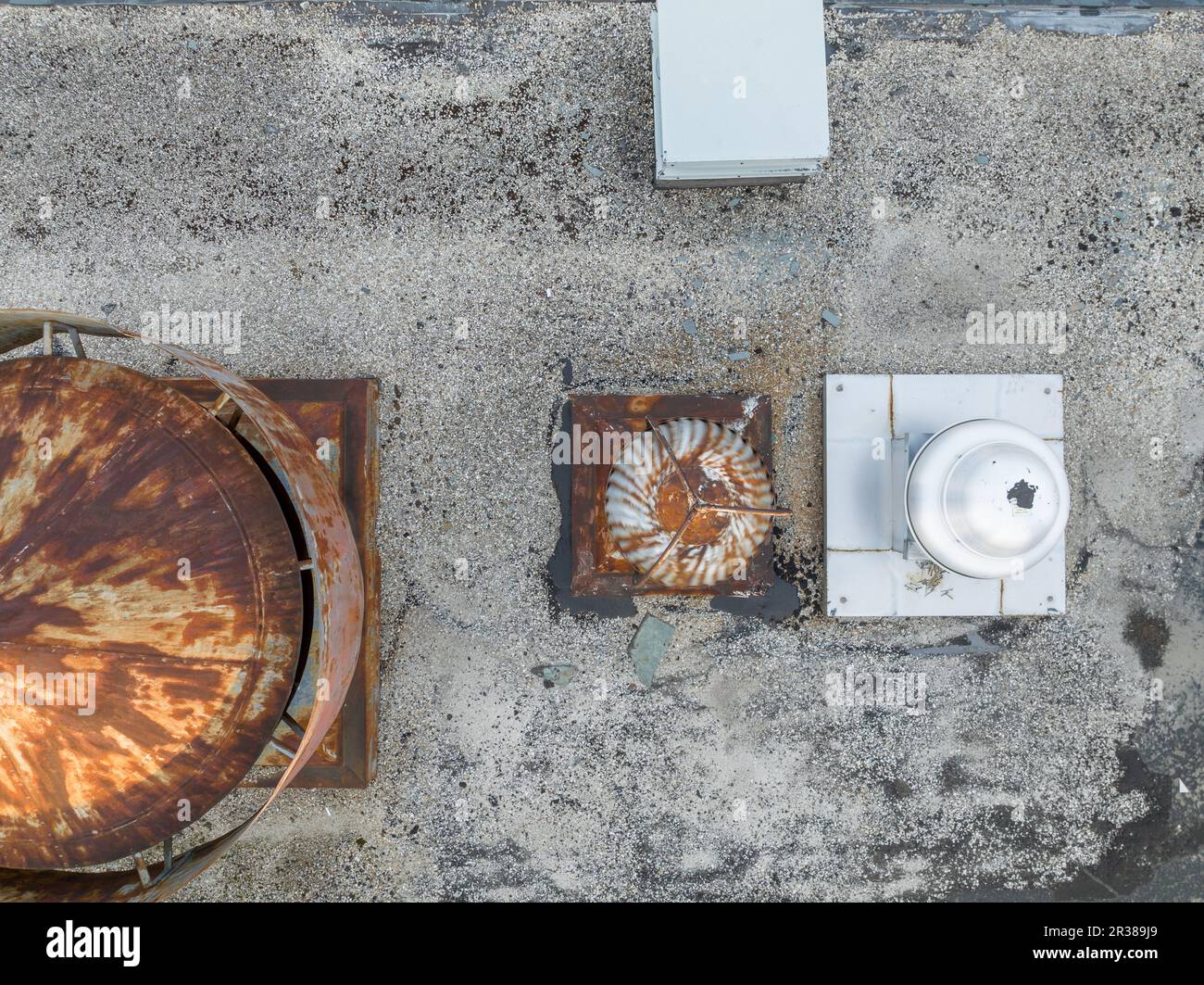 Vue aérienne d'un équipement HVAC rouillé d'aspect industriel sur un toit gris. Banque D'Images