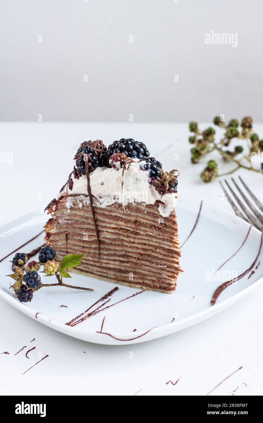 Une tranche de gâteau à la crêpe au chocolat et aux mûres Banque D'Images