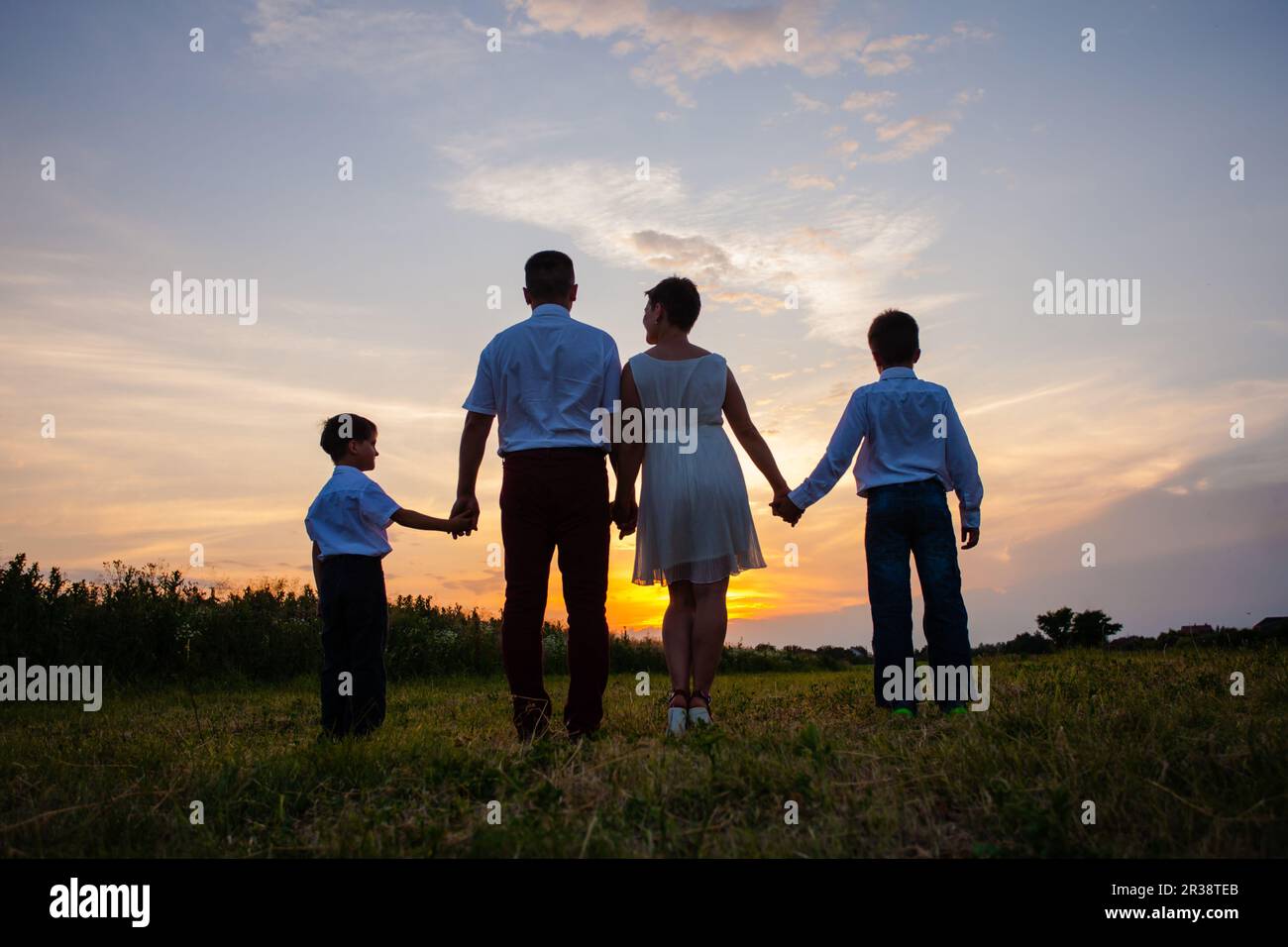 Famille heureuse sur l'arrière-plan de la coucher du soleil Banque D'Images