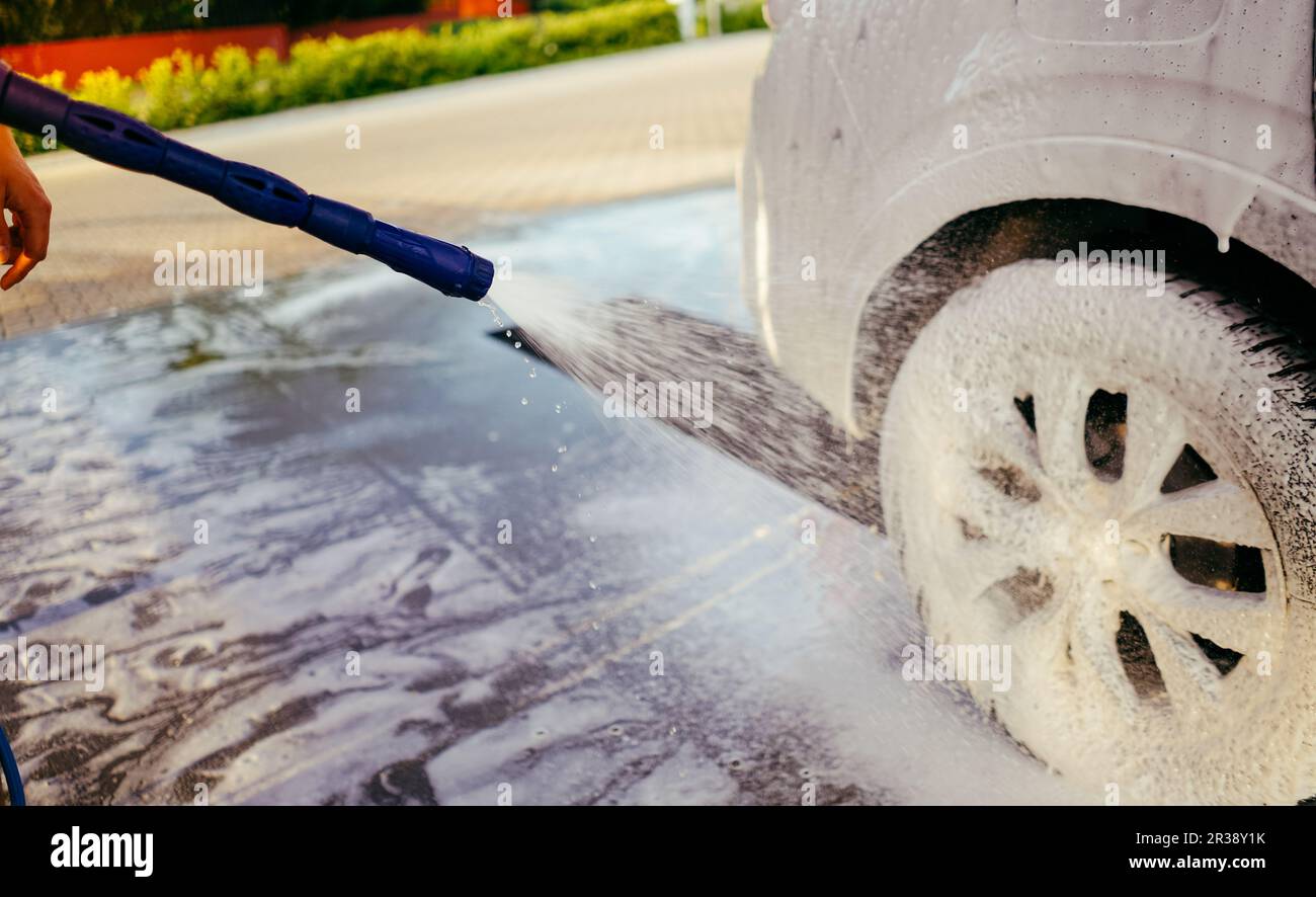 Mousser la voiture avec la mousse. Lavage de voiture. Homme lavant la voiture sur le service auto-lavant. Eau haute pression. Nettoyeur sous pression. Nettoyage de la voiture. Banque D'Images