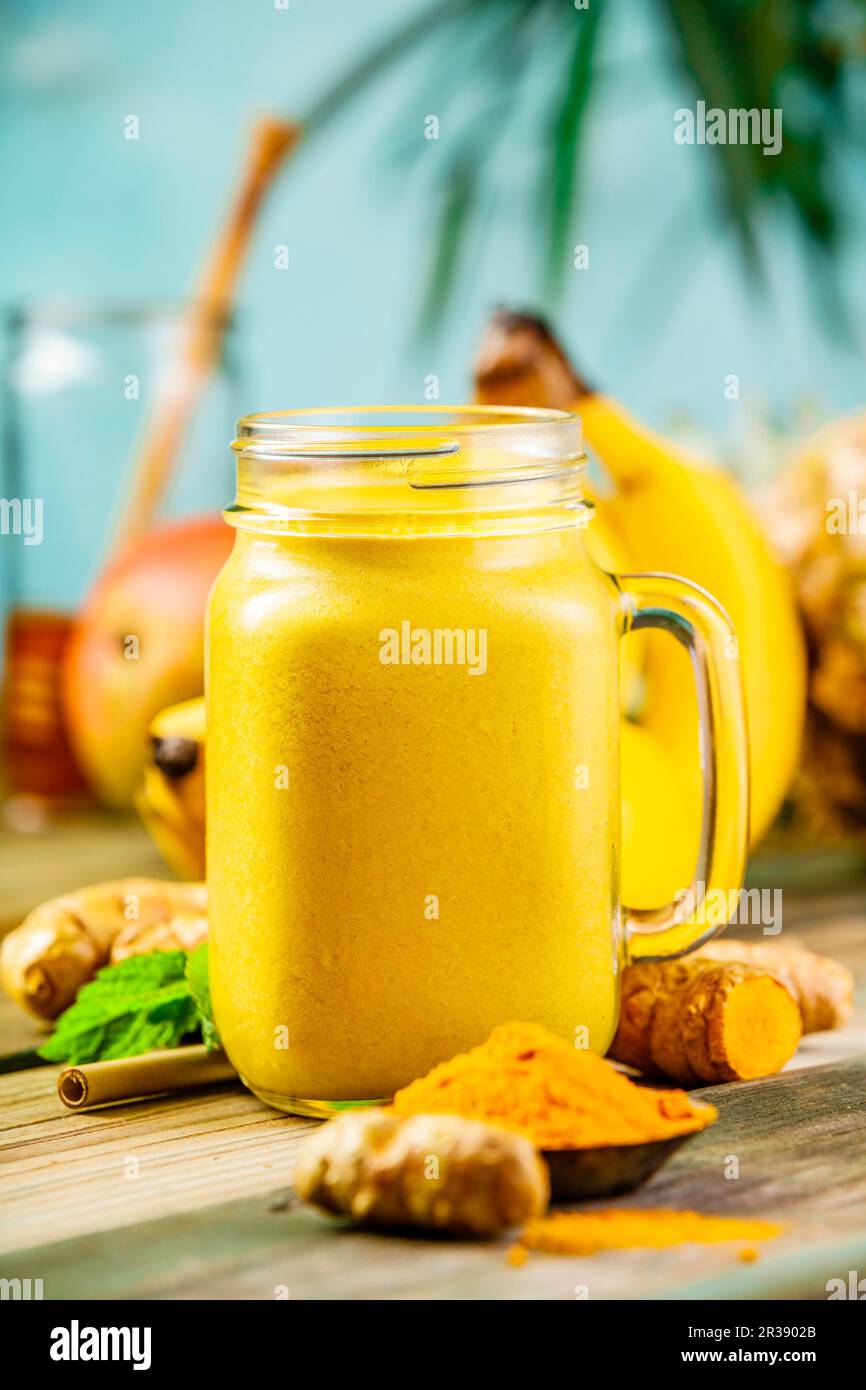 Smoothie aux fruits jaunes avec curcuma et ingrédients sur une table Banque D'Images