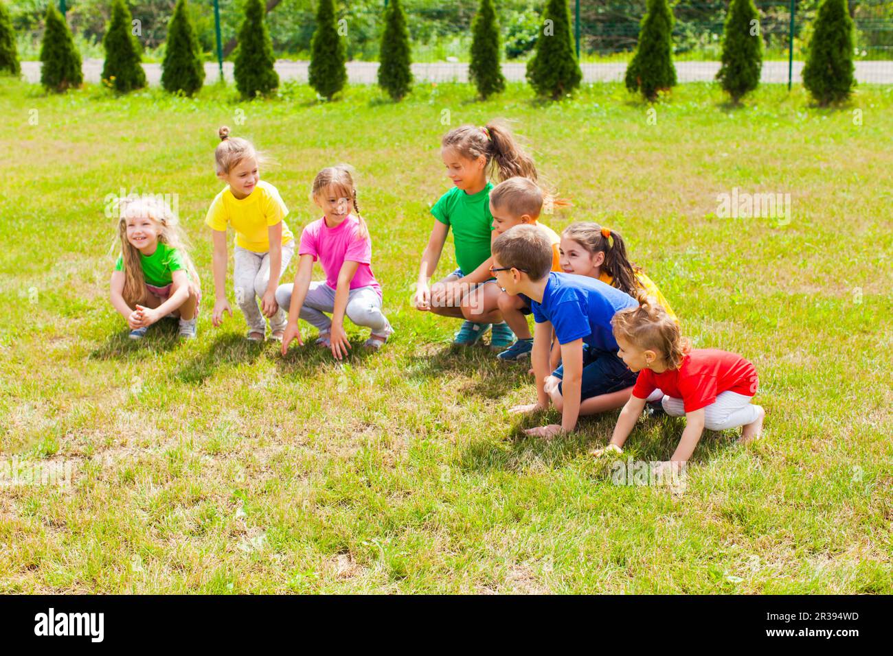 Des enfants qui s'accroupient prêts à sauter. Activités sportives Banque D'Images