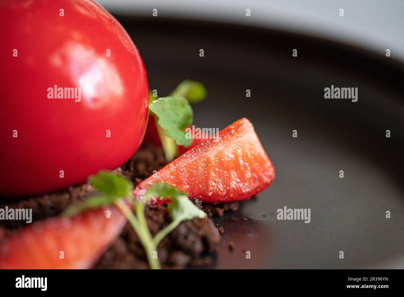 Dessert aux fraises. Gâteau au caillé en forme de sphère avec fraises et chapelure de brownie. Dessert rouge sur l'assiette noire. Mise au point sélective. Banque D'Images