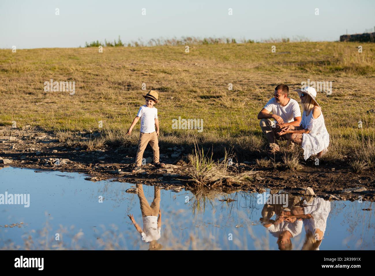 Promenade familiale près de l'étang et le garçon jette des cailloux Banque D'Images