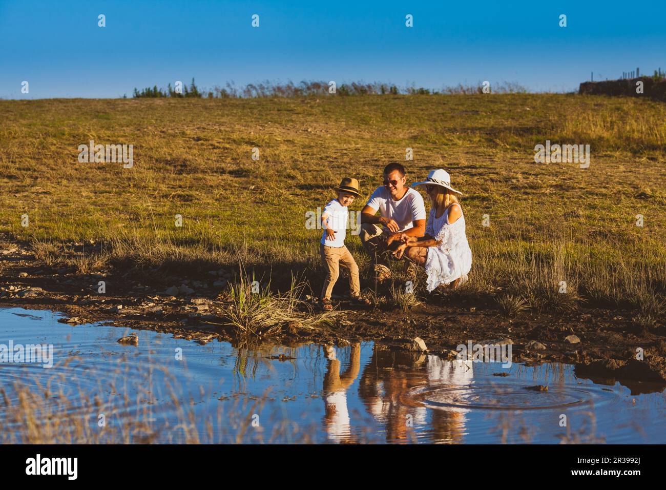 Promenade familiale près de l'étang, garçon jette des cailloux Banque D'Images