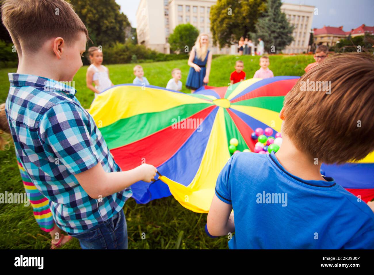 Happy kids playing jeu actif avec parachute coloré Banque D'Images