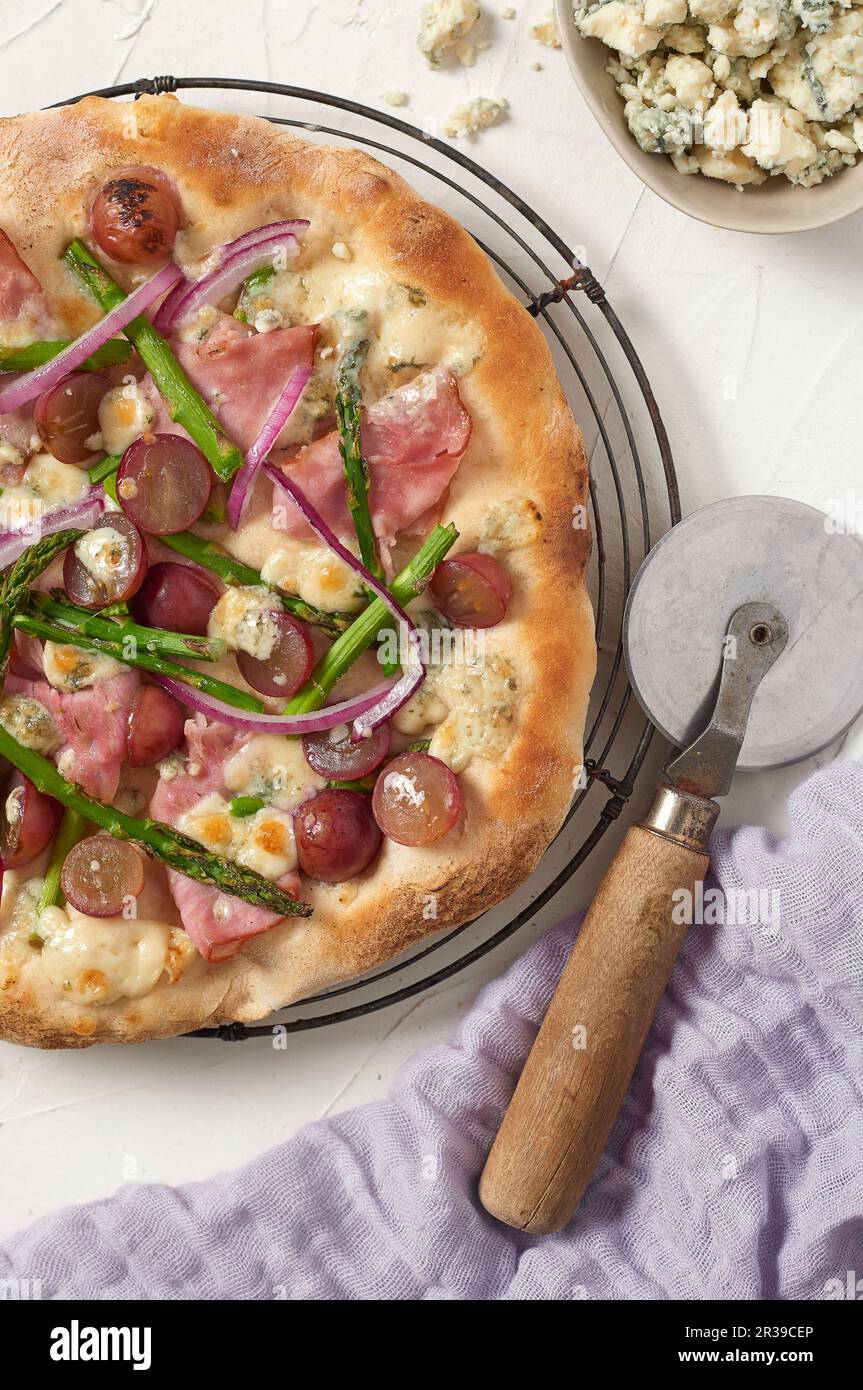 Pizza avec jambon, raisins, asperges et fromage bleu Banque D'Images