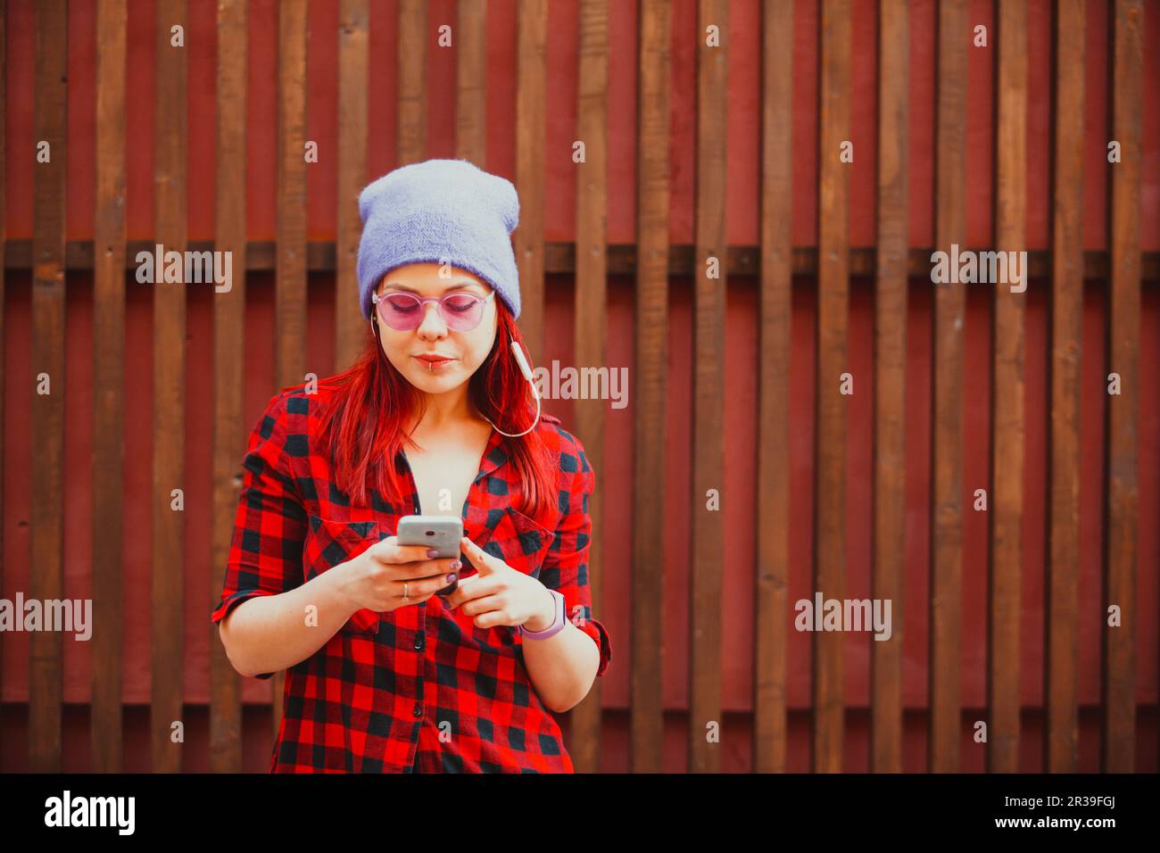Une fille hipster élégante et informelle écoute de la musique à l'aide d'un smartphone et d'un casque Banque D'Images