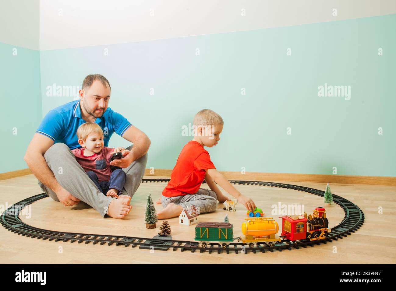 Un père heureux et des enfants jouent un jouet ferroviaire Banque D'Images