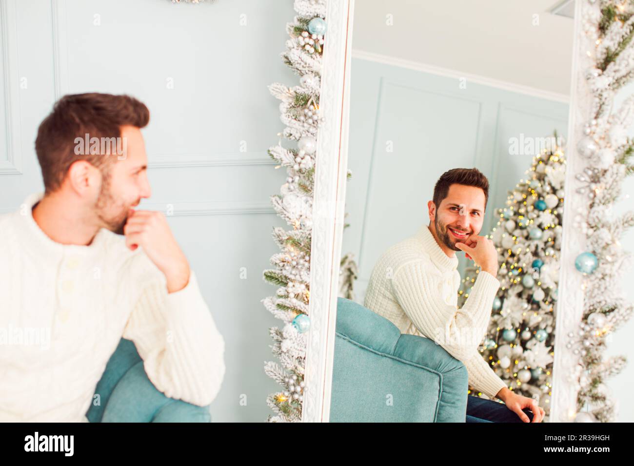 Homme dans un studio décoré de Noël regardant dans le miroir Banque D'Images