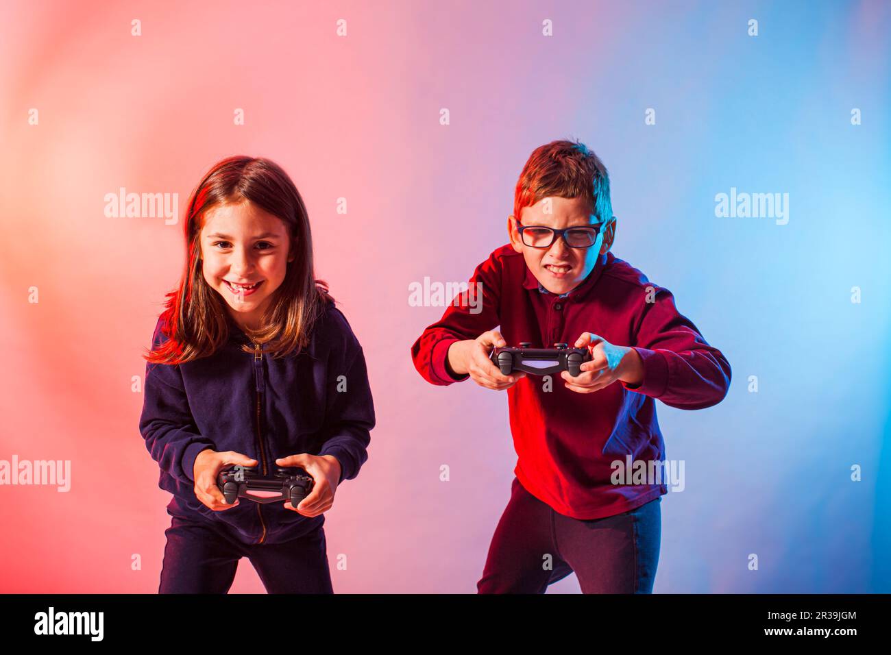 Les enfants excités avec des joysticks jouant à un jeu virtuel intéressant Banque D'Images