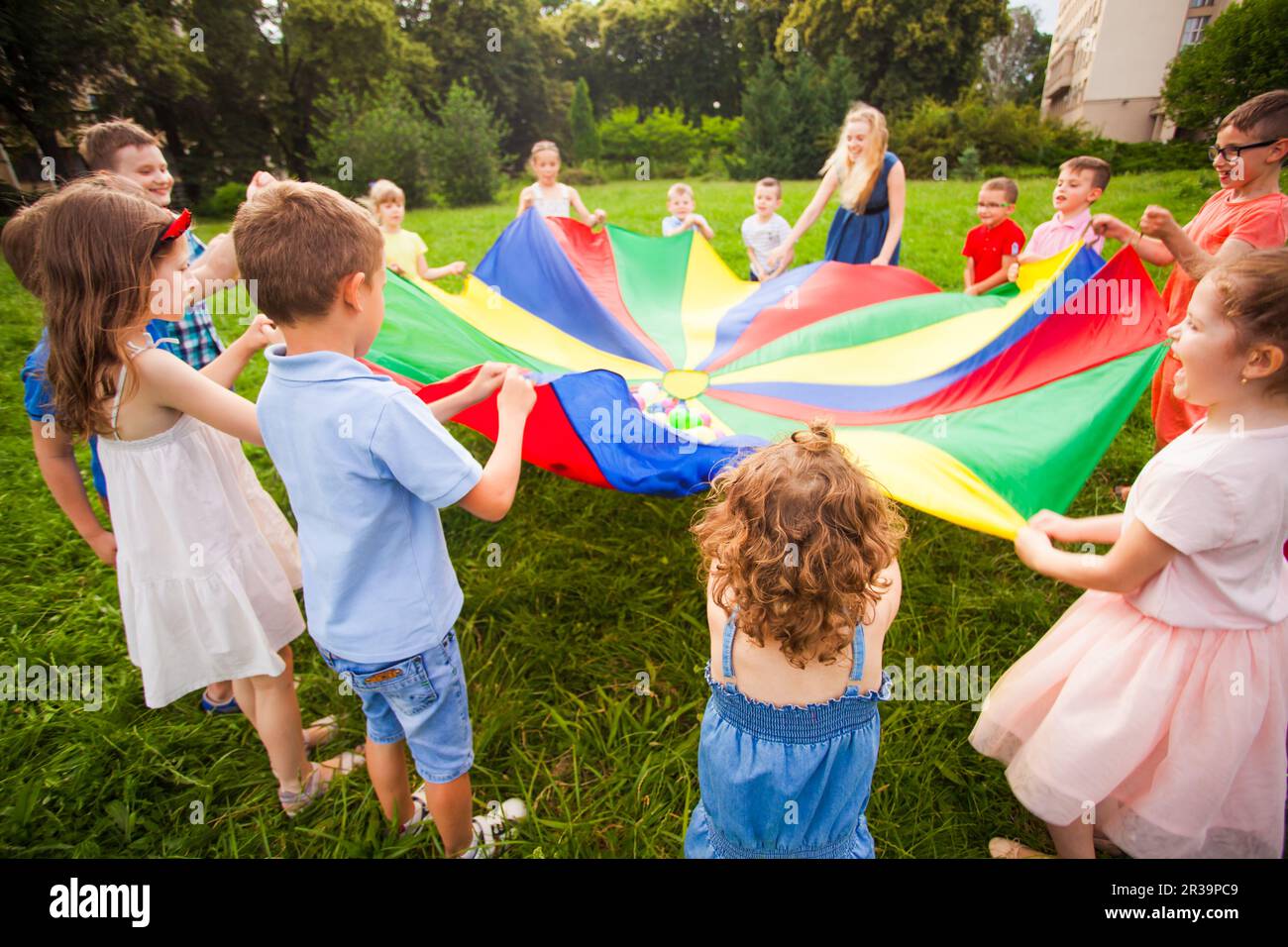 Des enfants heureux tenant le parachute pendant le jeu amusant Banque D'Images