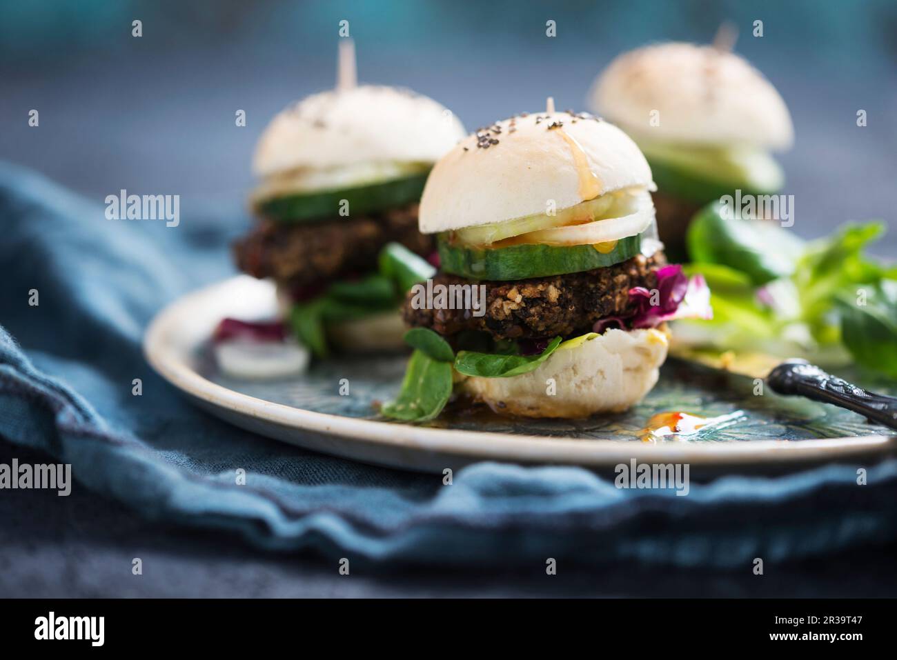 Mini burgers végétaliens avec beignets de lentilles de béluga, laitue d'agneau, radicchio, concombre, oignons et sauce Chili Banque D'Images