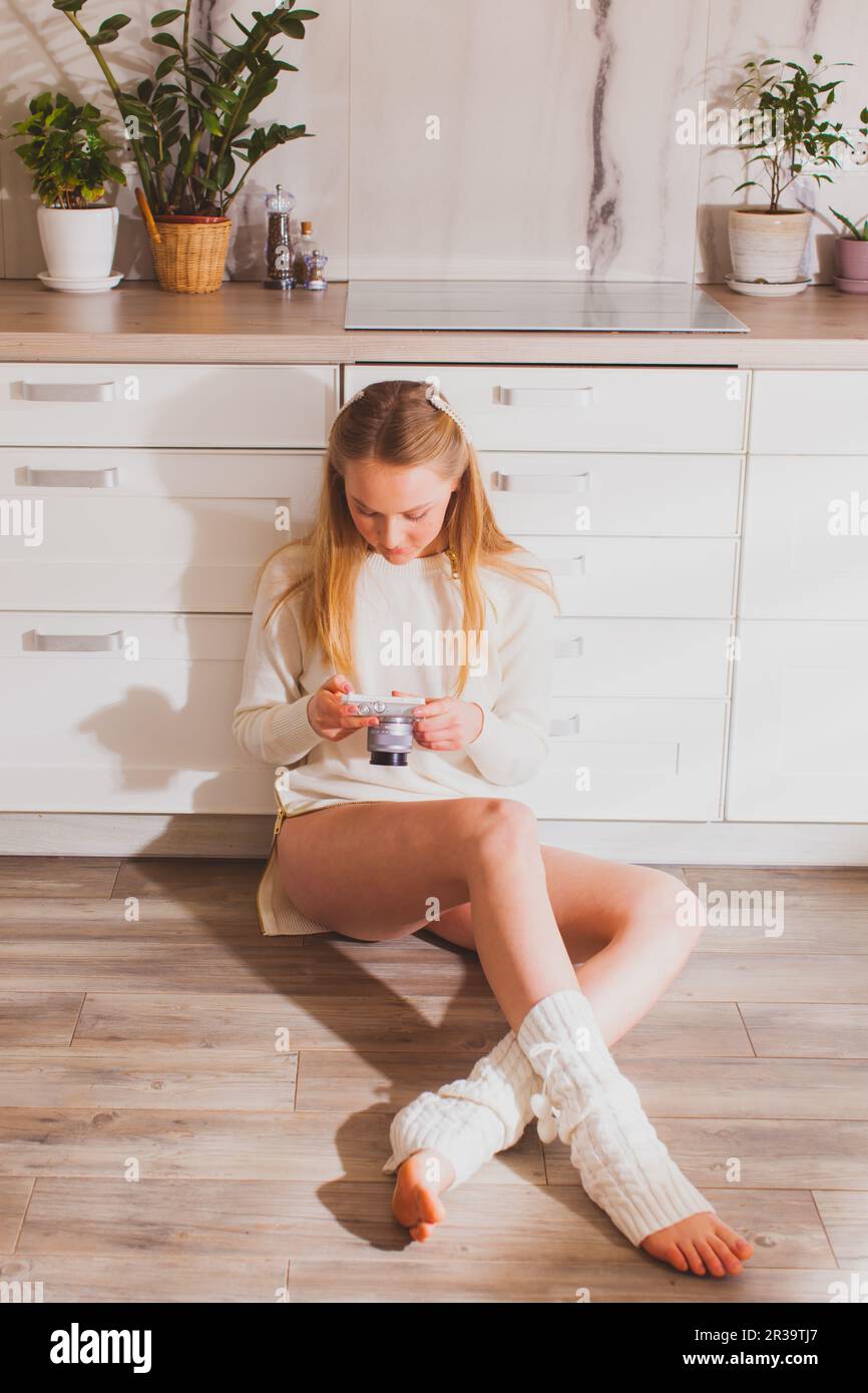 Jeune fille blonde regardant l'appareil photo dans ses mains Banque D'Images