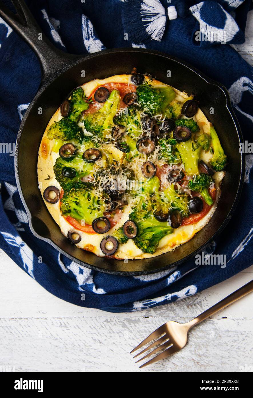 Une pizza de Socca avec des légumes dans une poêle en fonte Banque D'Images