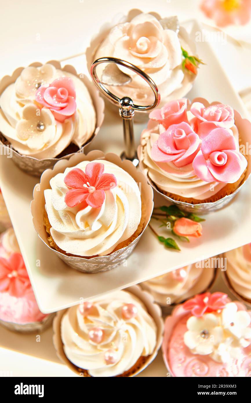 Petits gâteaux festifs décorés de garnitures crème et de fleurs de sucre Banque D'Images