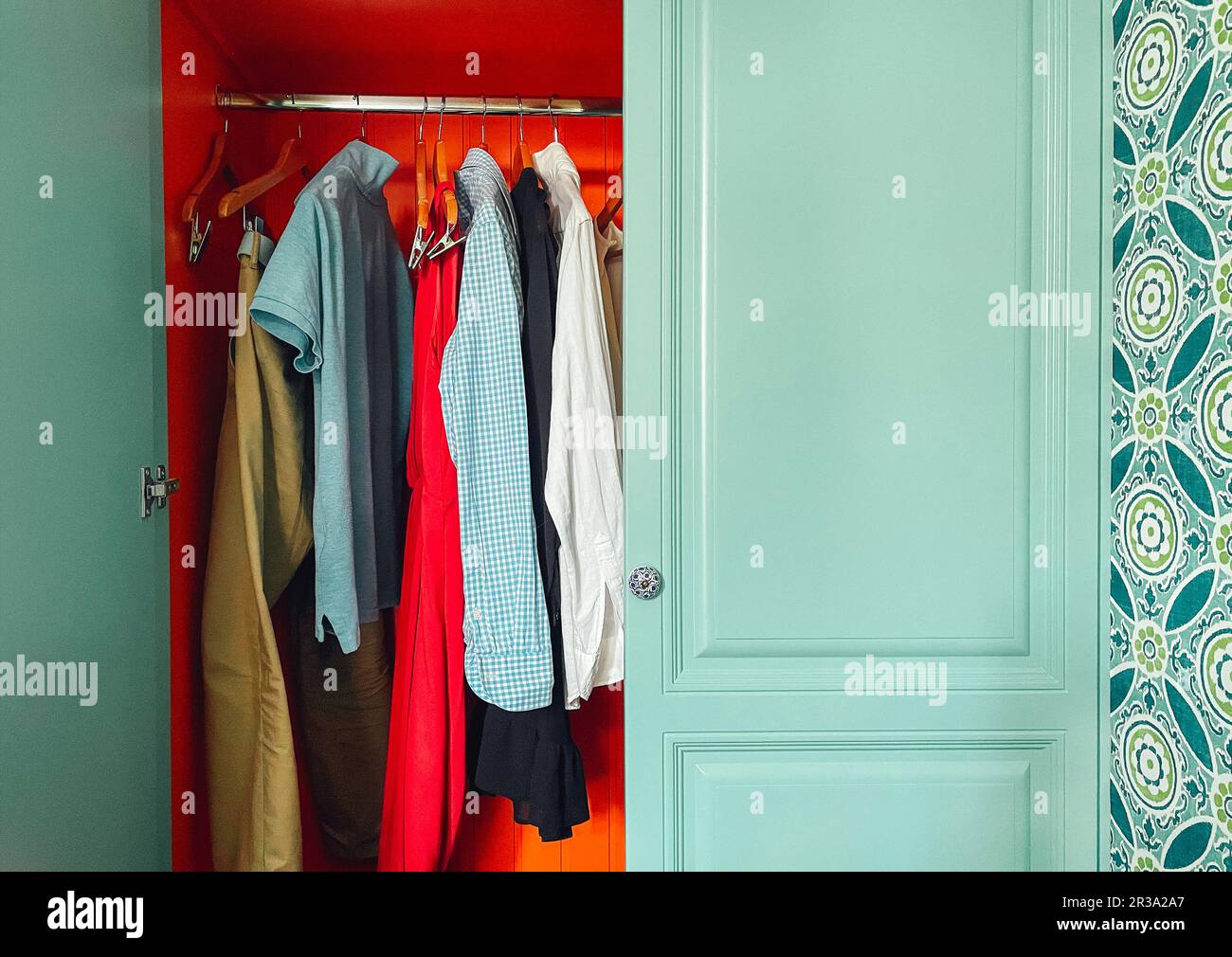 Armoire en bois bleu avec porte ouverte. Été femme et homme décontracté porter sur les épaules dans le placard moderne. Jeans, polos, chemisiers et robes en wardrob Banque D'Images