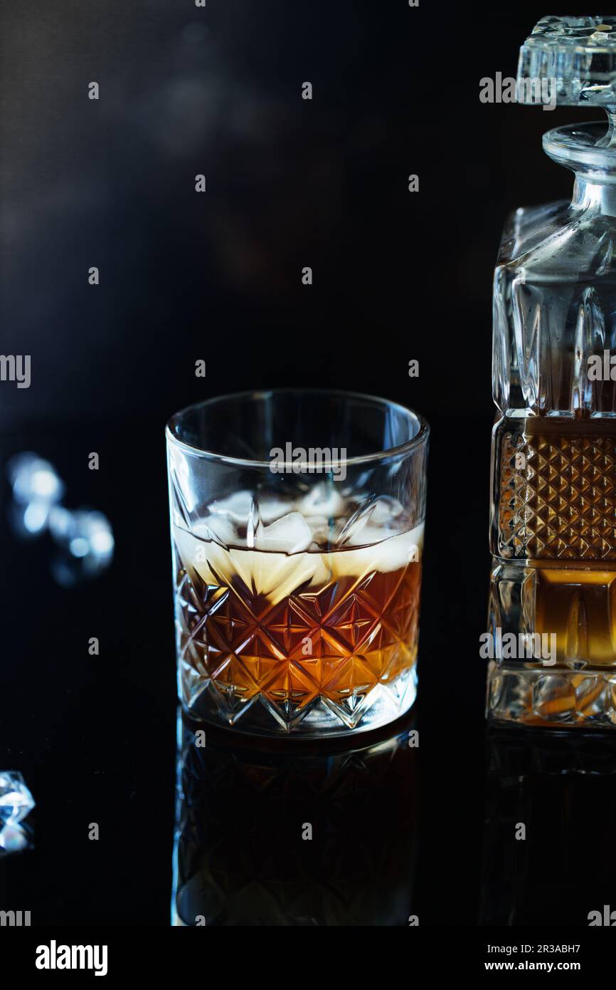 Verre de whisky ou de bourbon avec glace sur table en pierre noire. Verre de whisky avec glace et un carré de Banque D'Images