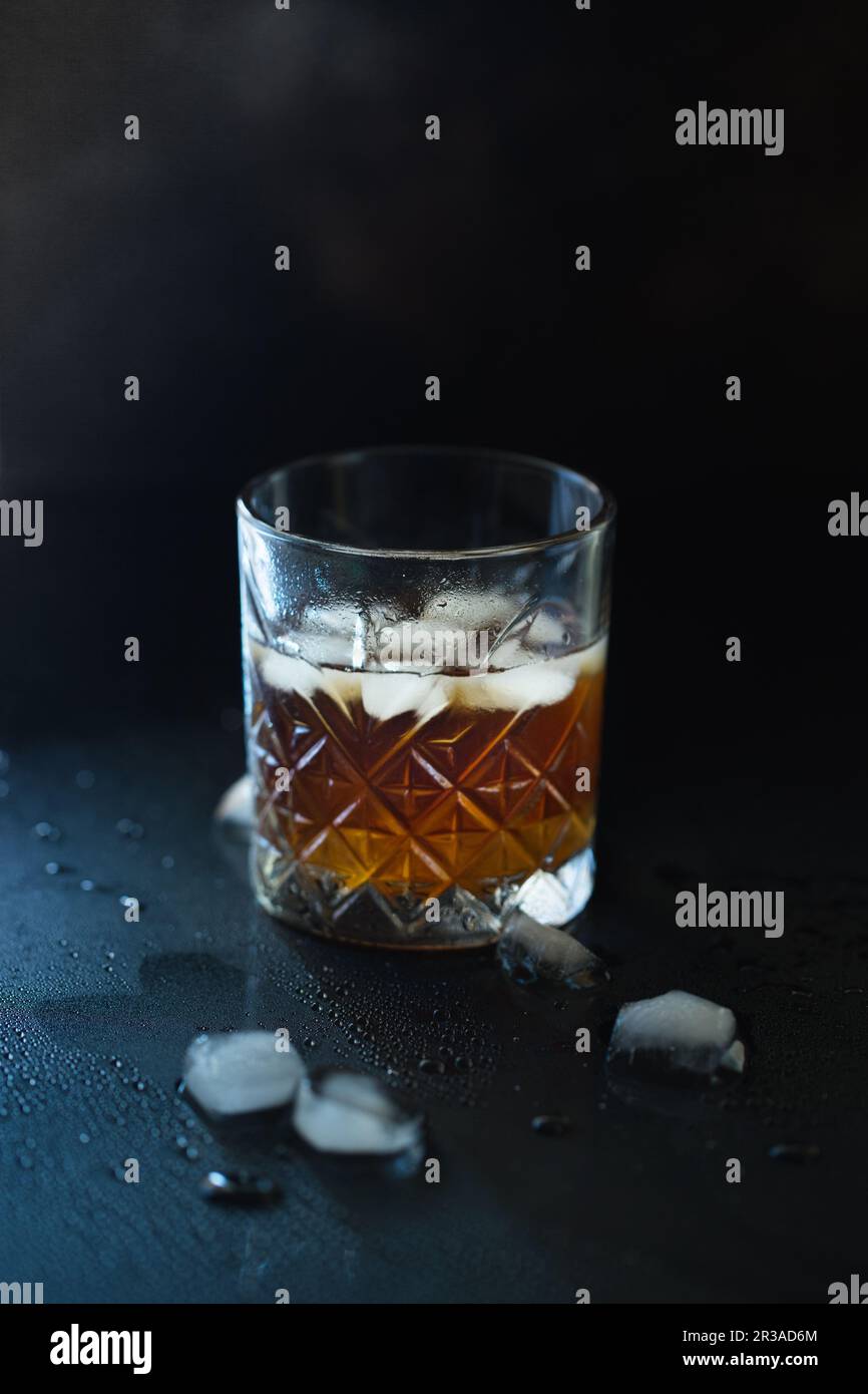 Verre de whisky ou de bourbon avec glace sur table en pierre noire. Verre de whisky avec glace et un carré de Banque D'Images