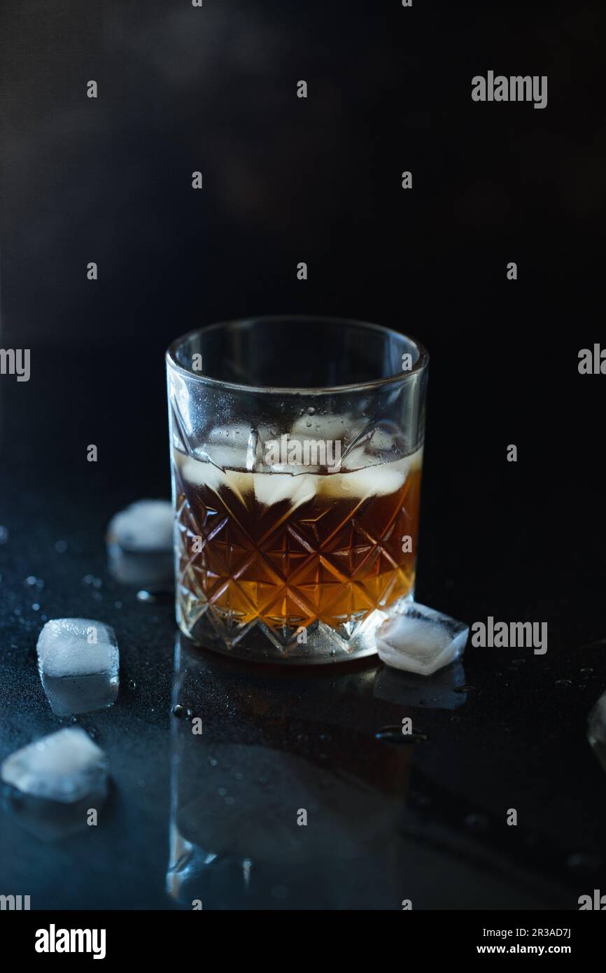 Verre de whisky ou de bourbon avec glace sur table en pierre noire. Verre de whisky avec glace et un carré de Banque D'Images