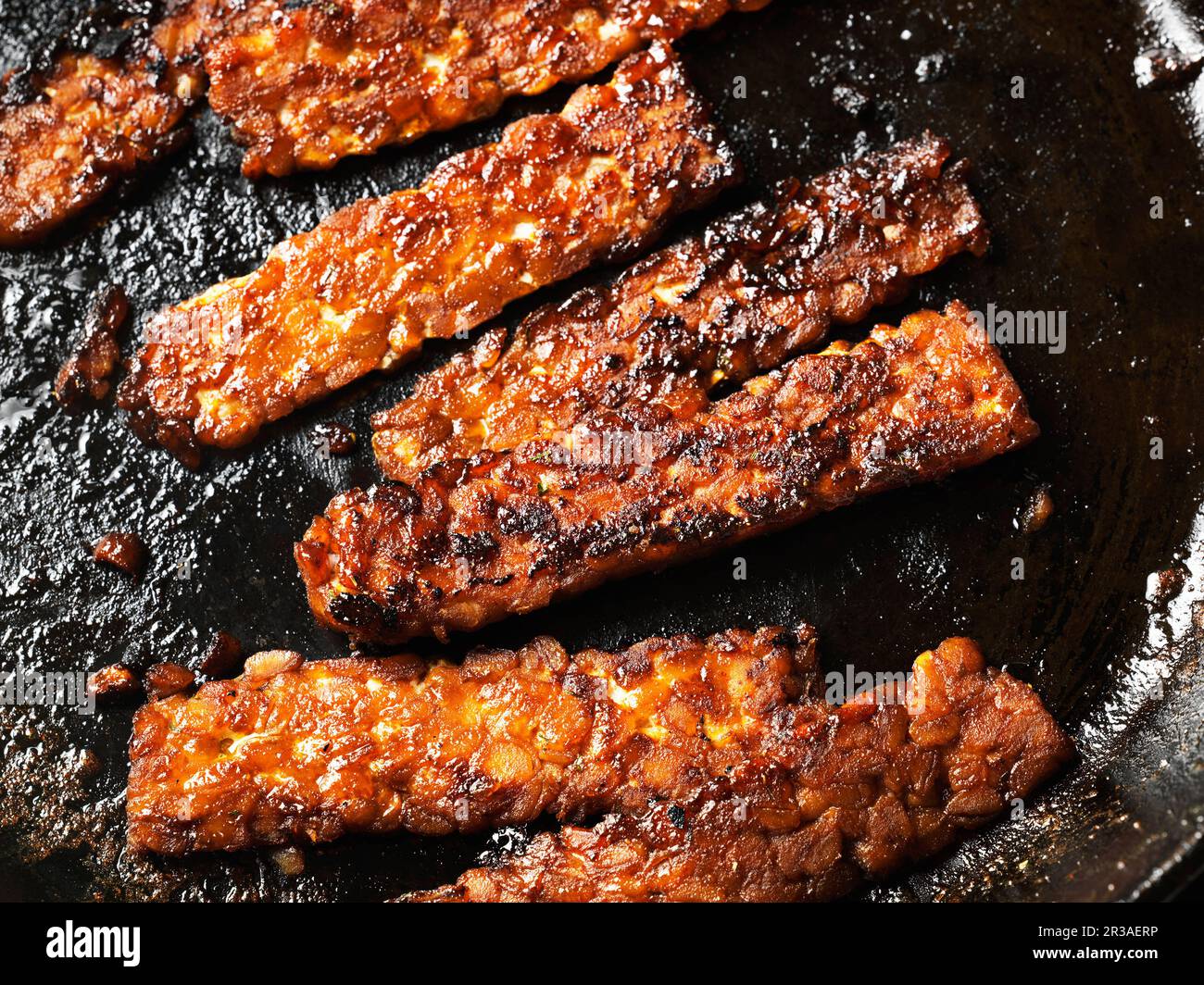 Tempeh tranches de bacon dans une poêle en fonte Banque D'Images