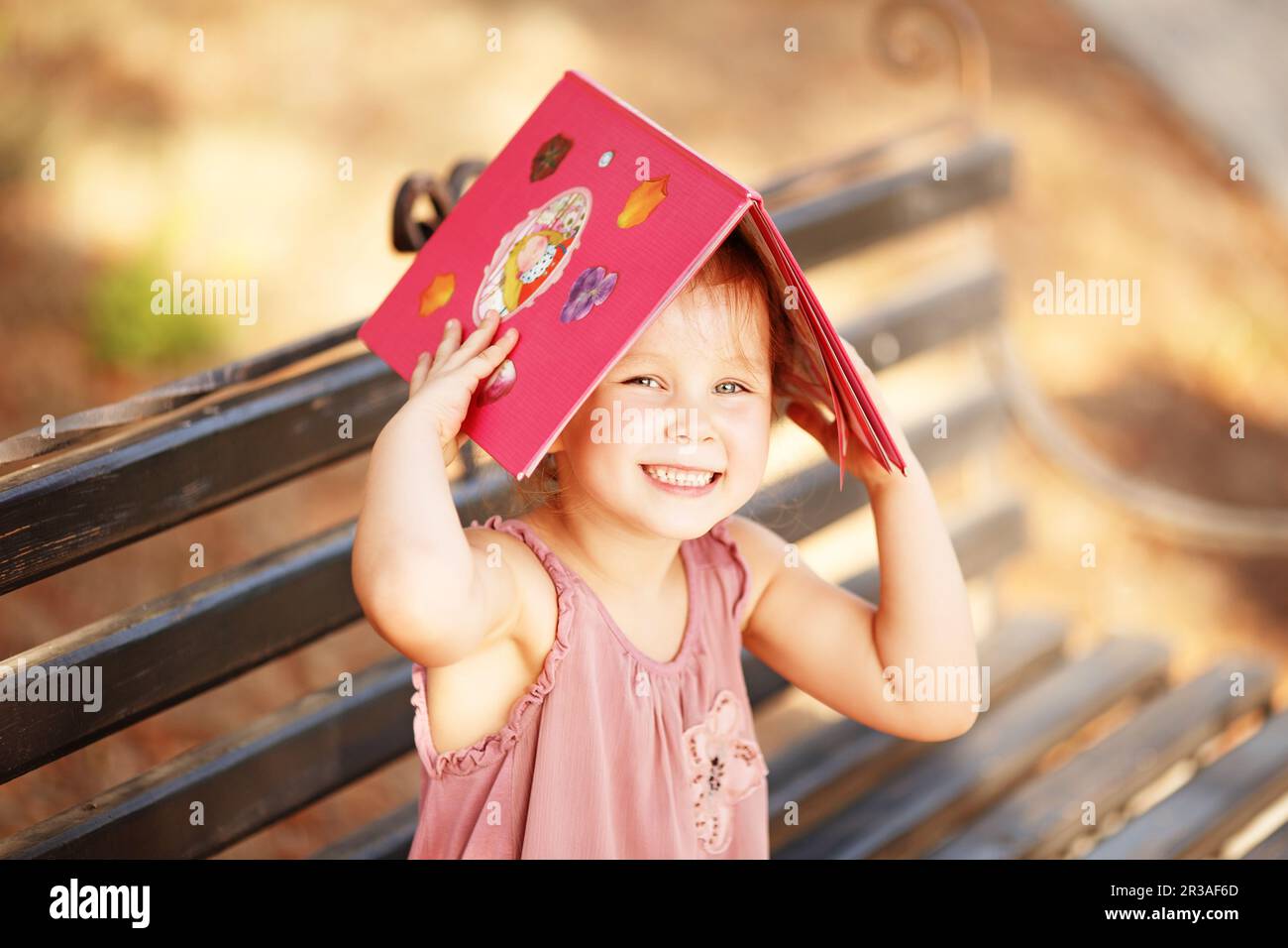 Portrait d'une petite fille en train de rire avec un livre sur son dirigez-vous vers l'extérieur Banque D'Images