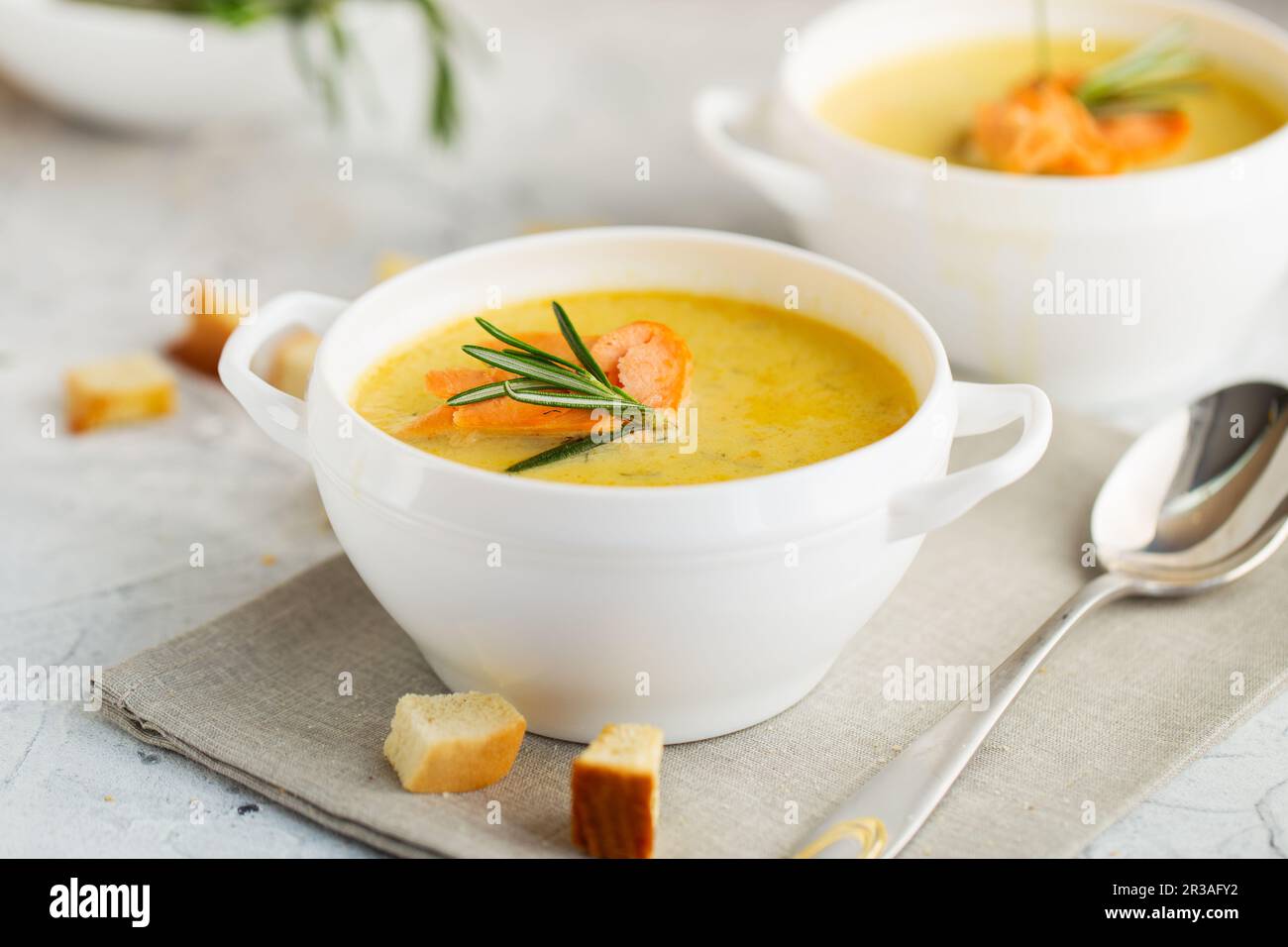 Soupe à la crème de poisson avec saumon, fromage, pommes de terre et herbes dans des bols à soupe blanche. Banque D'Images