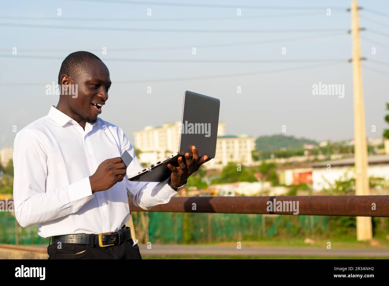 copie de l'image spatiale d'un homme africain portant un ordinateur portable, carte de crédit. geste joyeux Banque D'Images