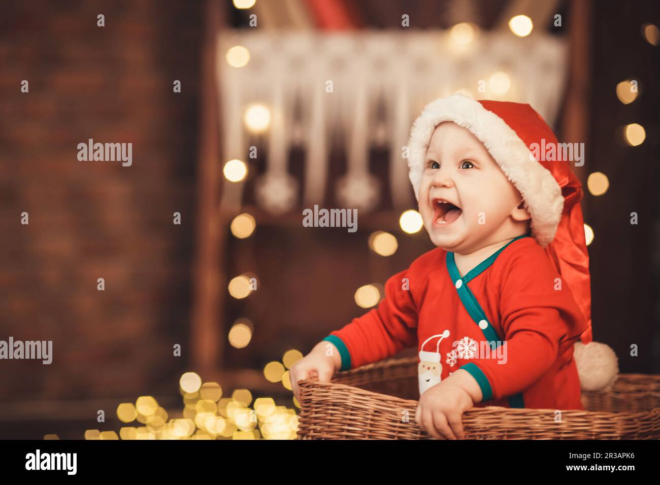 Petit garçon de père Noël dans un chapeau assis dans un panier en osier. Concept nouvel an et Noël Banque D'Images