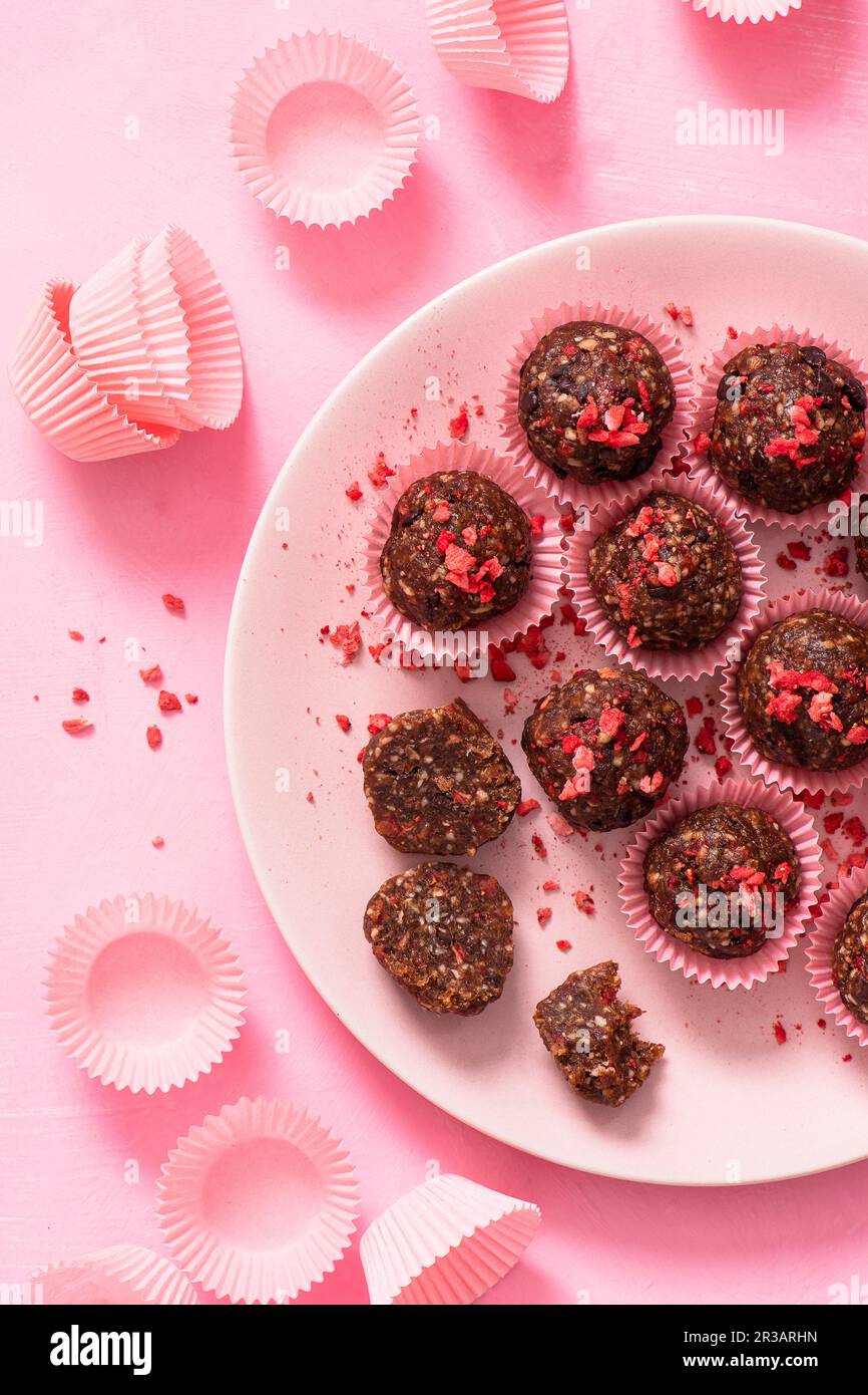 Boules de protéines énergétiques sans sucre, crues, végétaliennes, faites de dattes, d'amandes, d'huile de coco, de niches de cacao et de fraises lyophilisées Banque D'Images