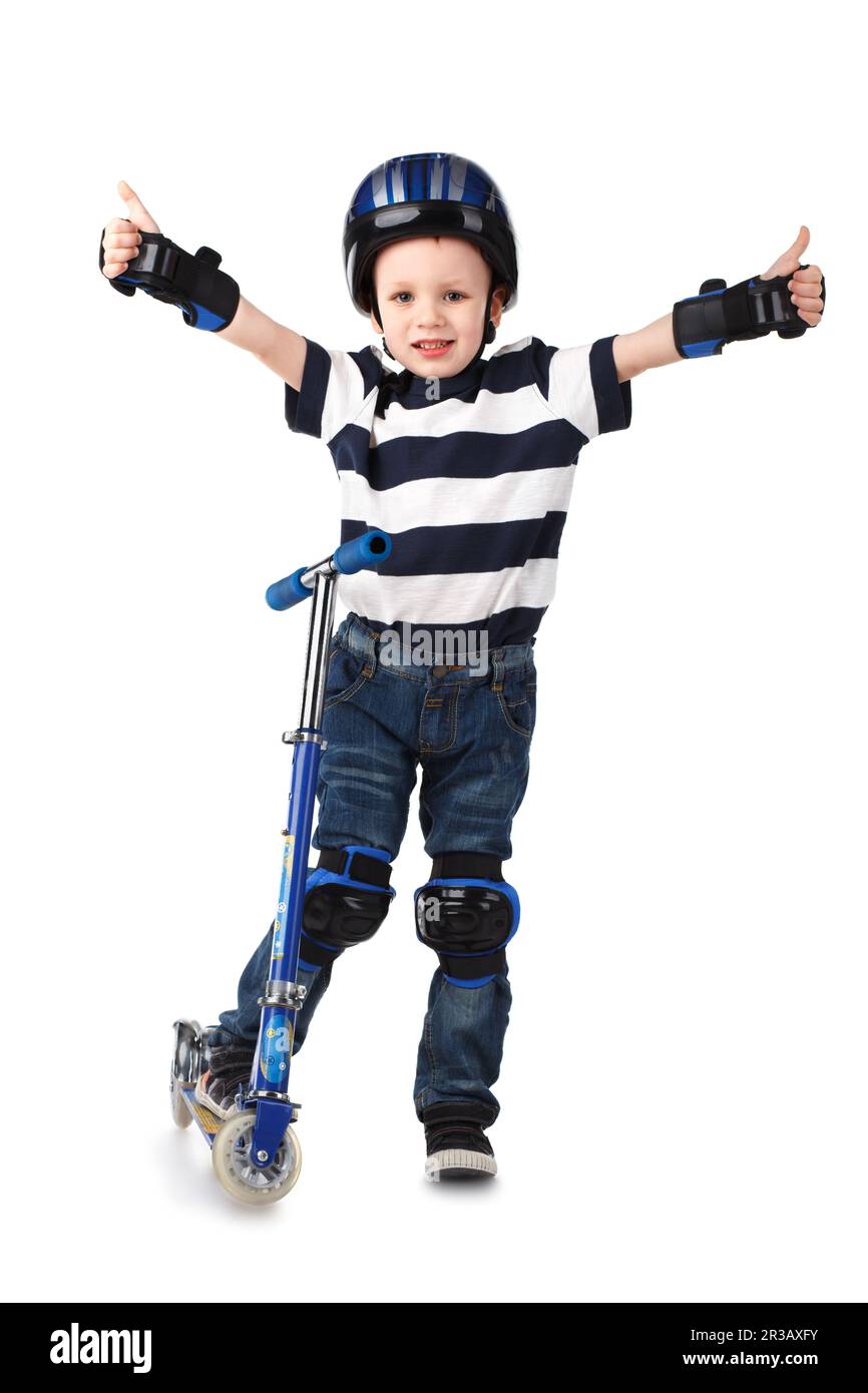 Petit garçon dans un casque de protection et dans le genou et le bras s'éroule à cheval sur son scooter Banque D'Images