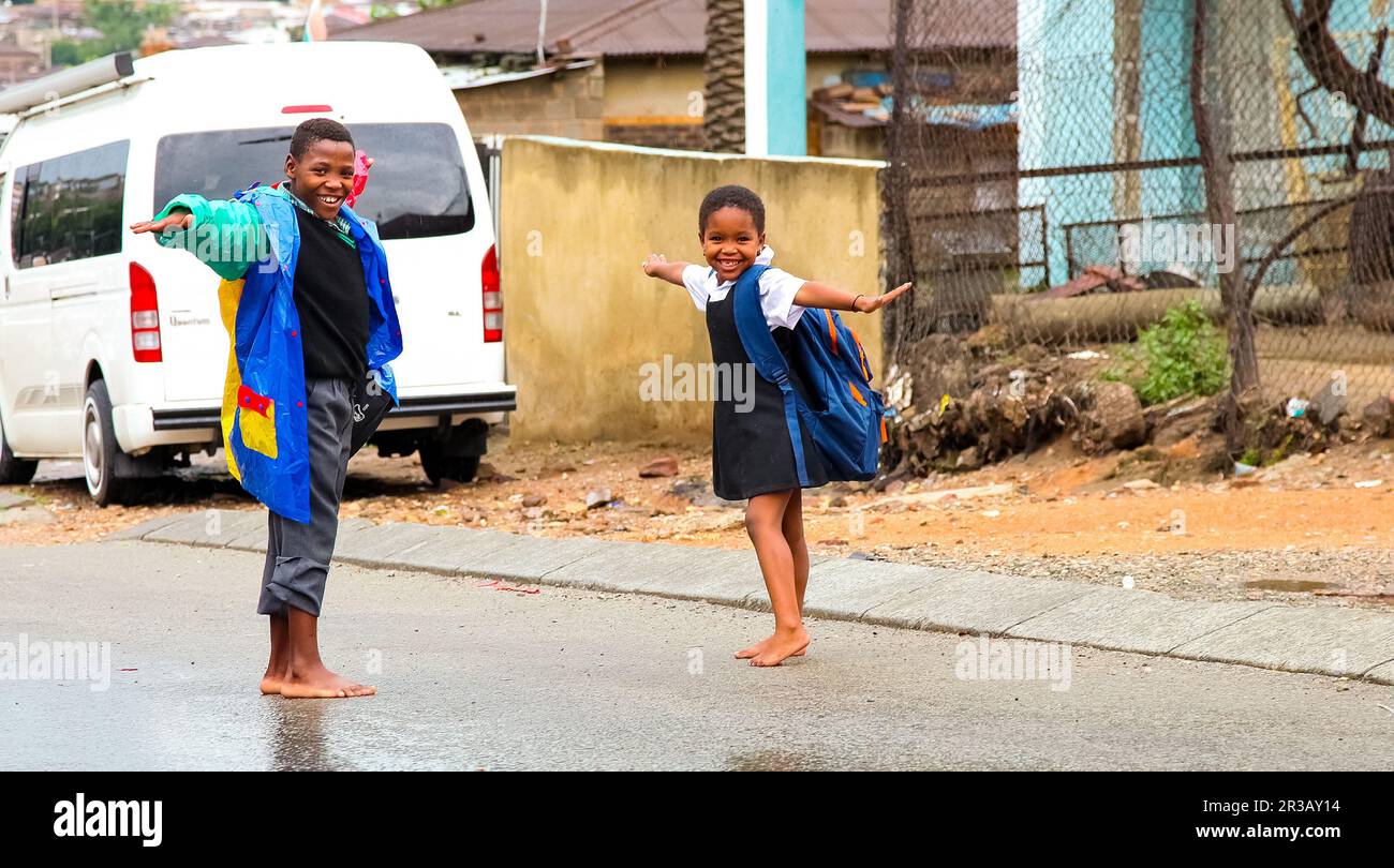 Des écoliers africains jouant sur une route principale dans le canton d'Alexandra, un établissement formel et informel Banque D'Images