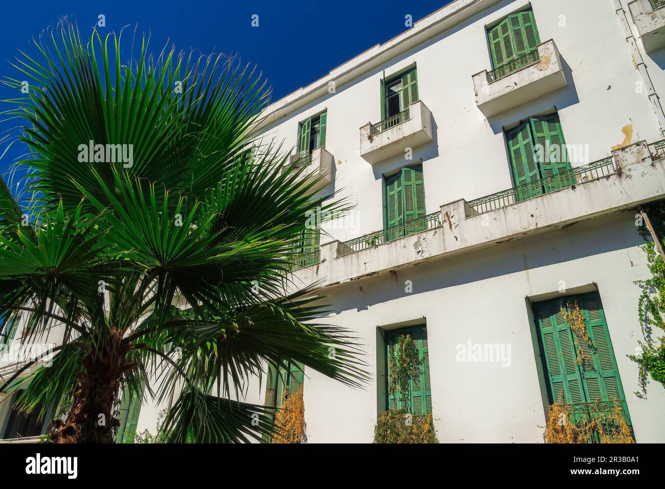 Un hôtel bas de 1930s avec une façade décalées et des volets en bois vert sous le ciel bleu d'été. Banque D'Images