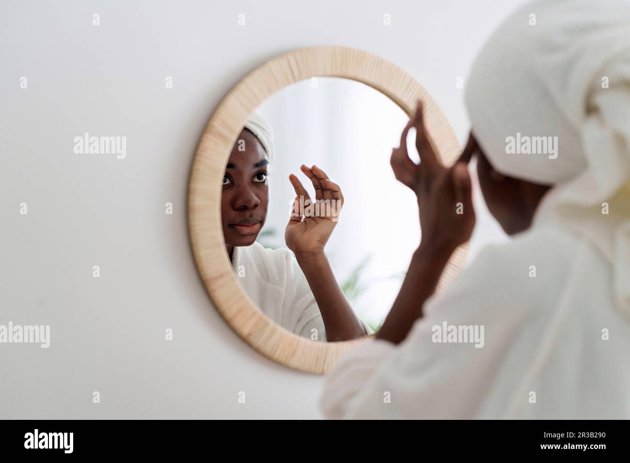 Femme faisant la routine de beauté regardant dans le miroir à la maison Banque D'Images