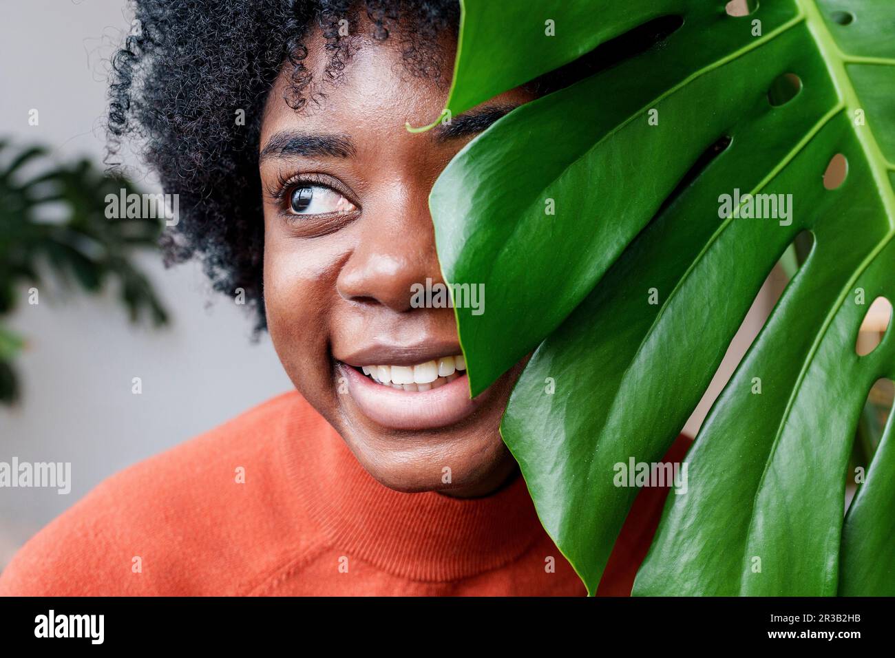 Jeune femme souriante avec une feuille de monstère Banque D'Images