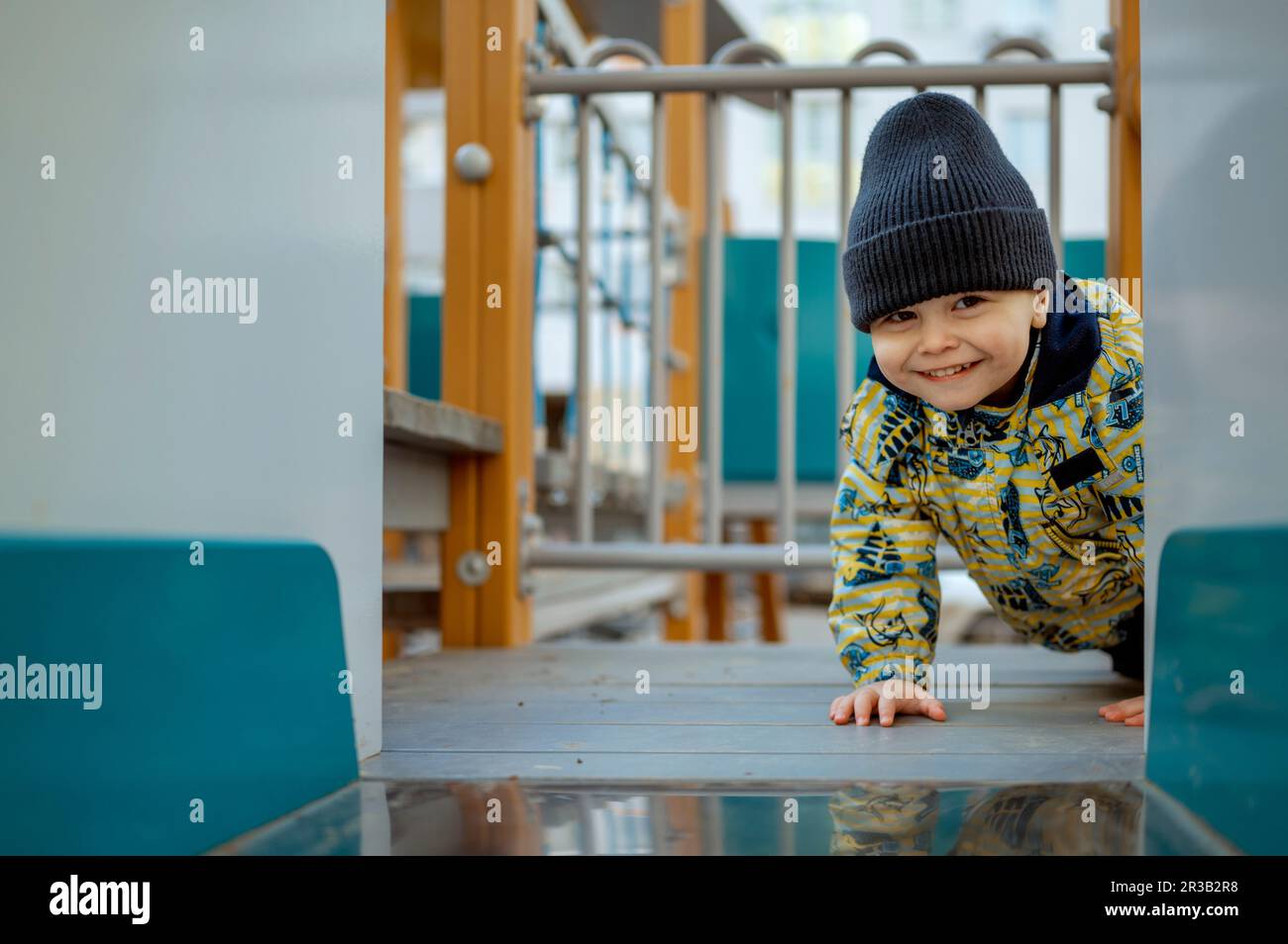 Un adorable garçon souriant s'élançant à l'aire de jeux Banque D'Images