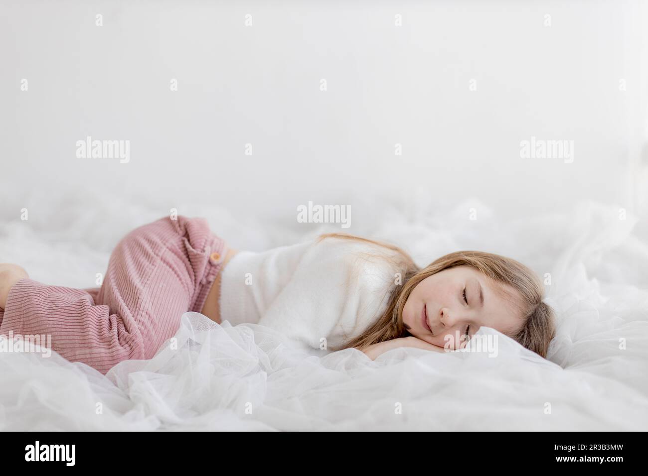 Fille dormant devant le mur blanc Banque D'Images