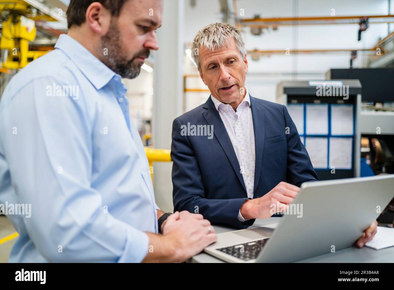 Un homme d'affaires qui a prévu de passer un ordinateur portable à l'usine avec un responsable Banque D'Images