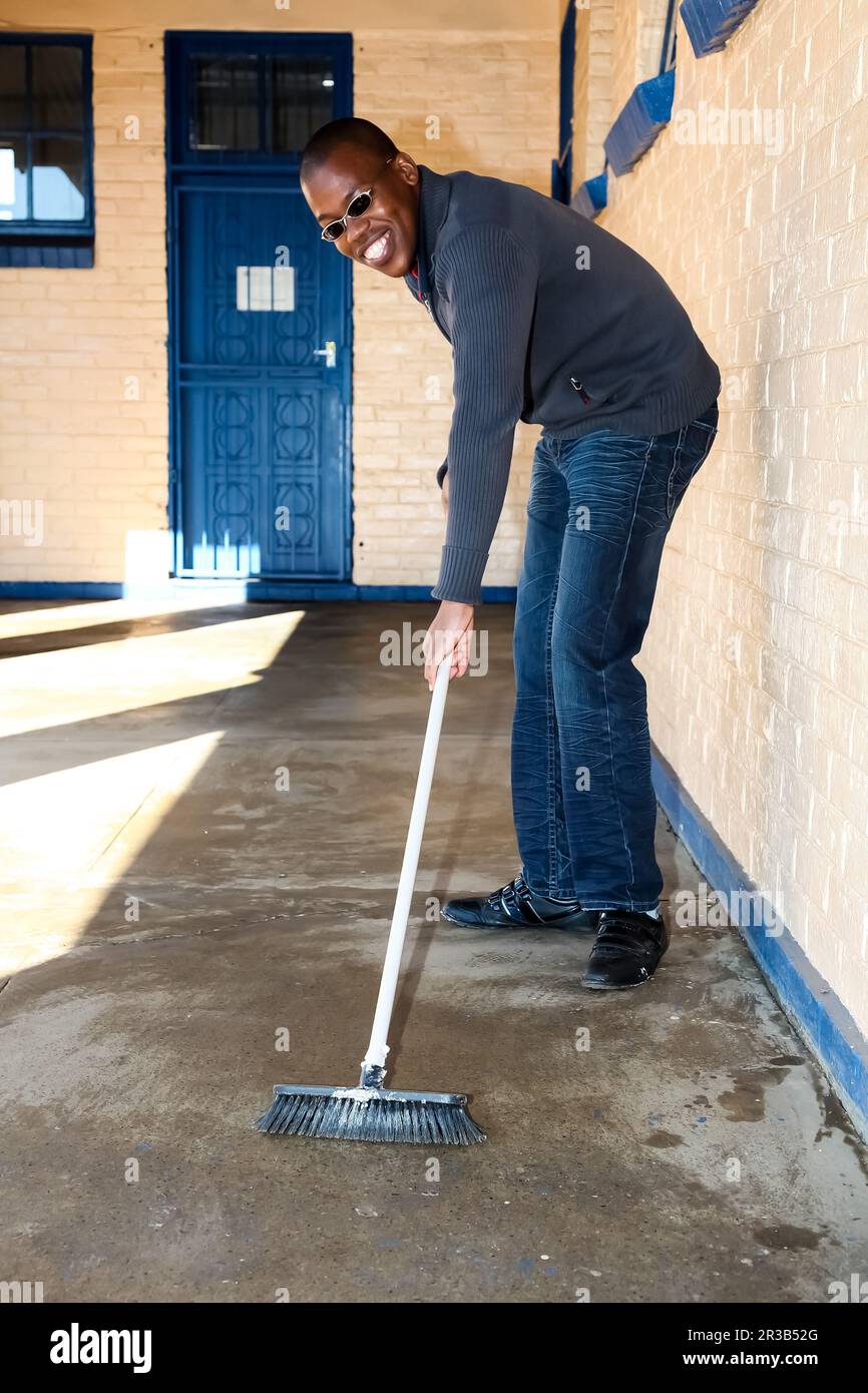 Un homme africain effectuant un travail de nettoyage volontaire de service communautaire à l'école de canton Banque D'Images