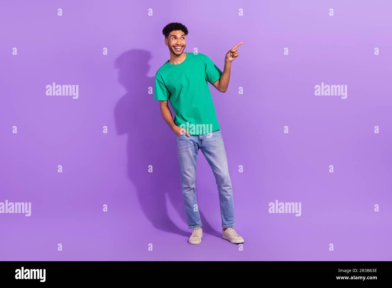 Photo du corps complet du jeune homme porter un t-shirt vert diriger le  doigt vide espace profiter de la nouvelle bande-annonce de film isolée sur  fond violet de couleur Photo Stock -