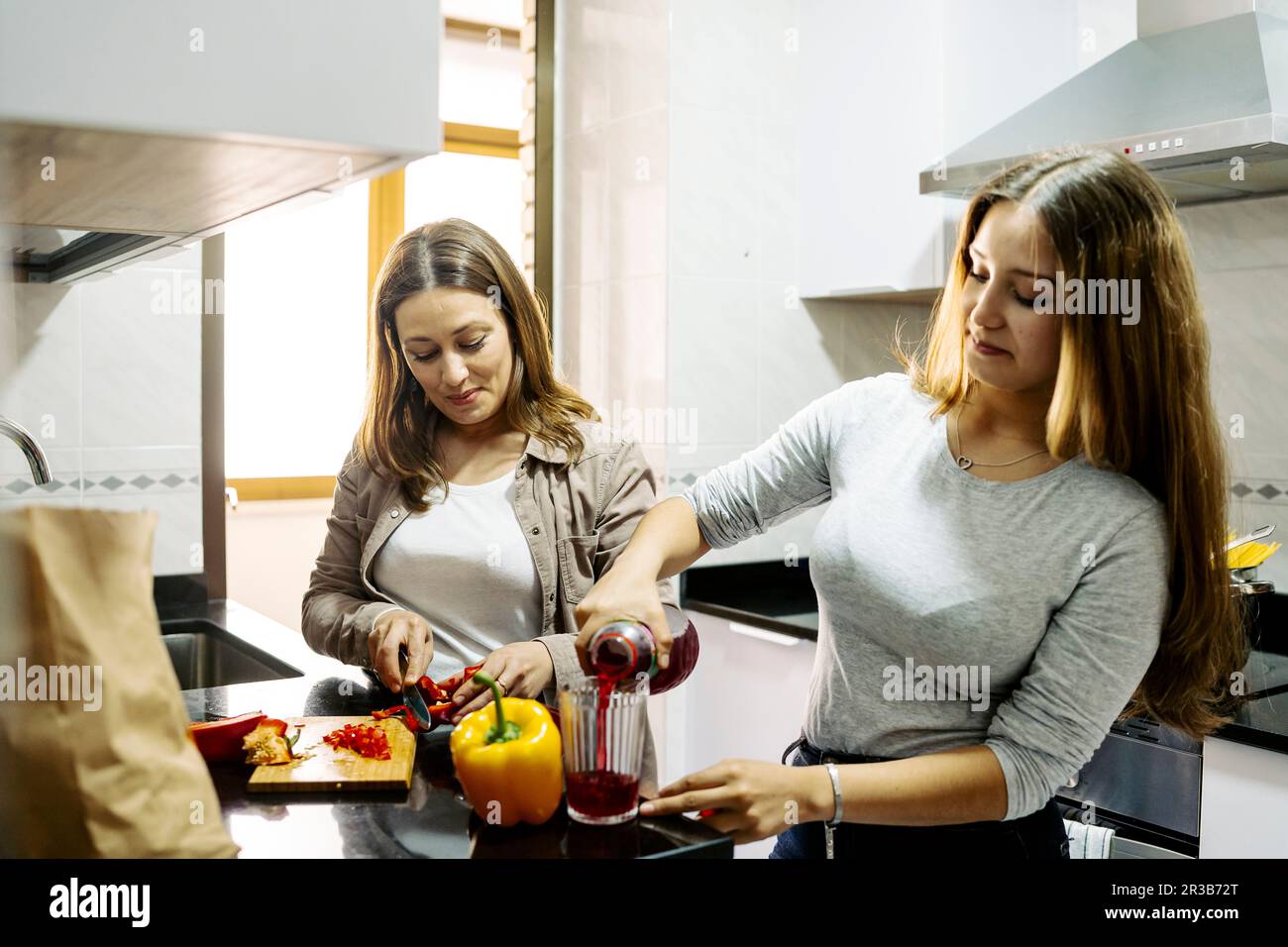 Fille aidant la mère à préparer la nourriture dans la cuisine à la maison Banque D'Images