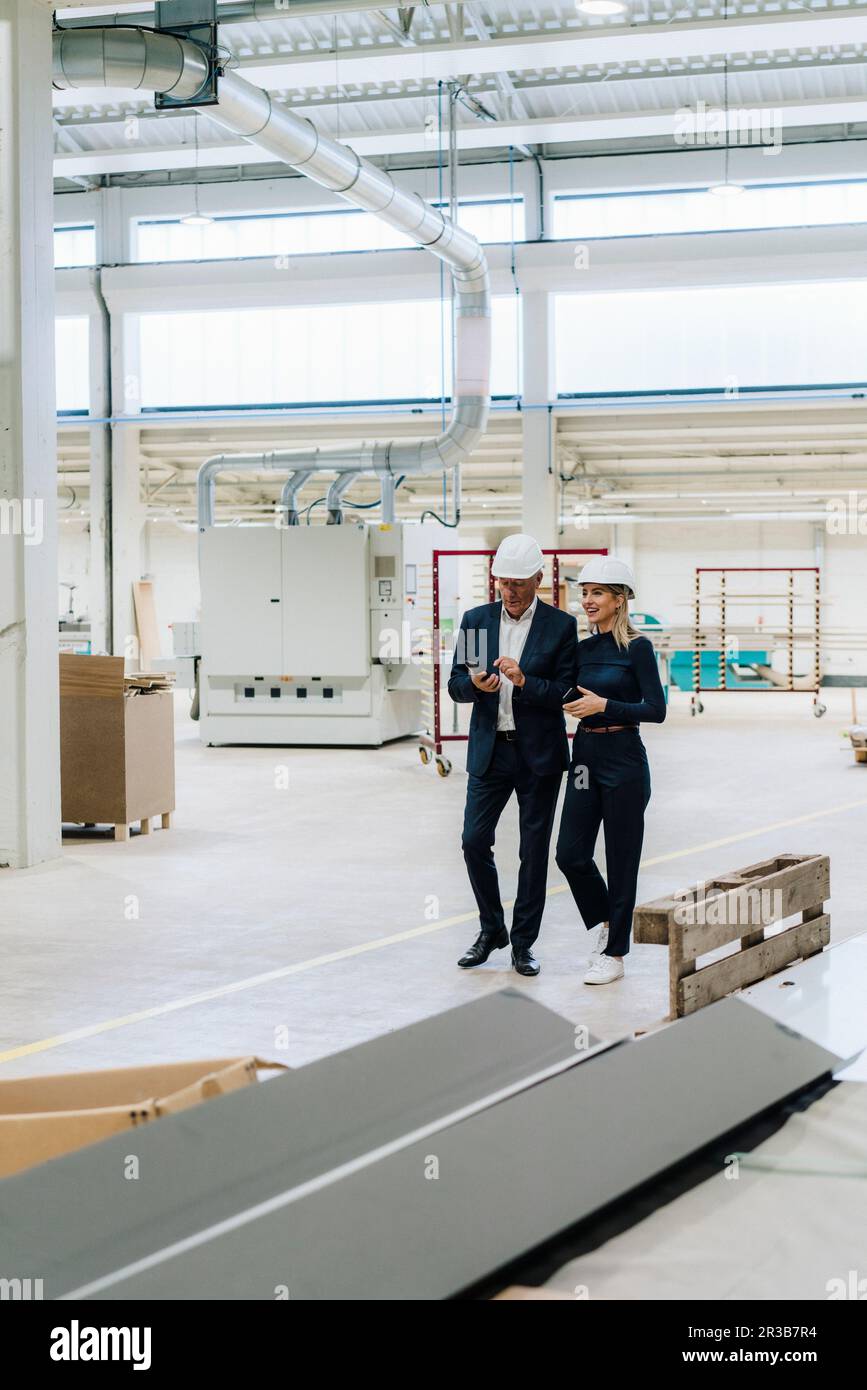 Homme d'affaires et collègue qui marchent ensemble dans l'industrie Banque D'Images Homme d'affaires et collègue qui marchent ensemble dans l'industrie Banque D'Images