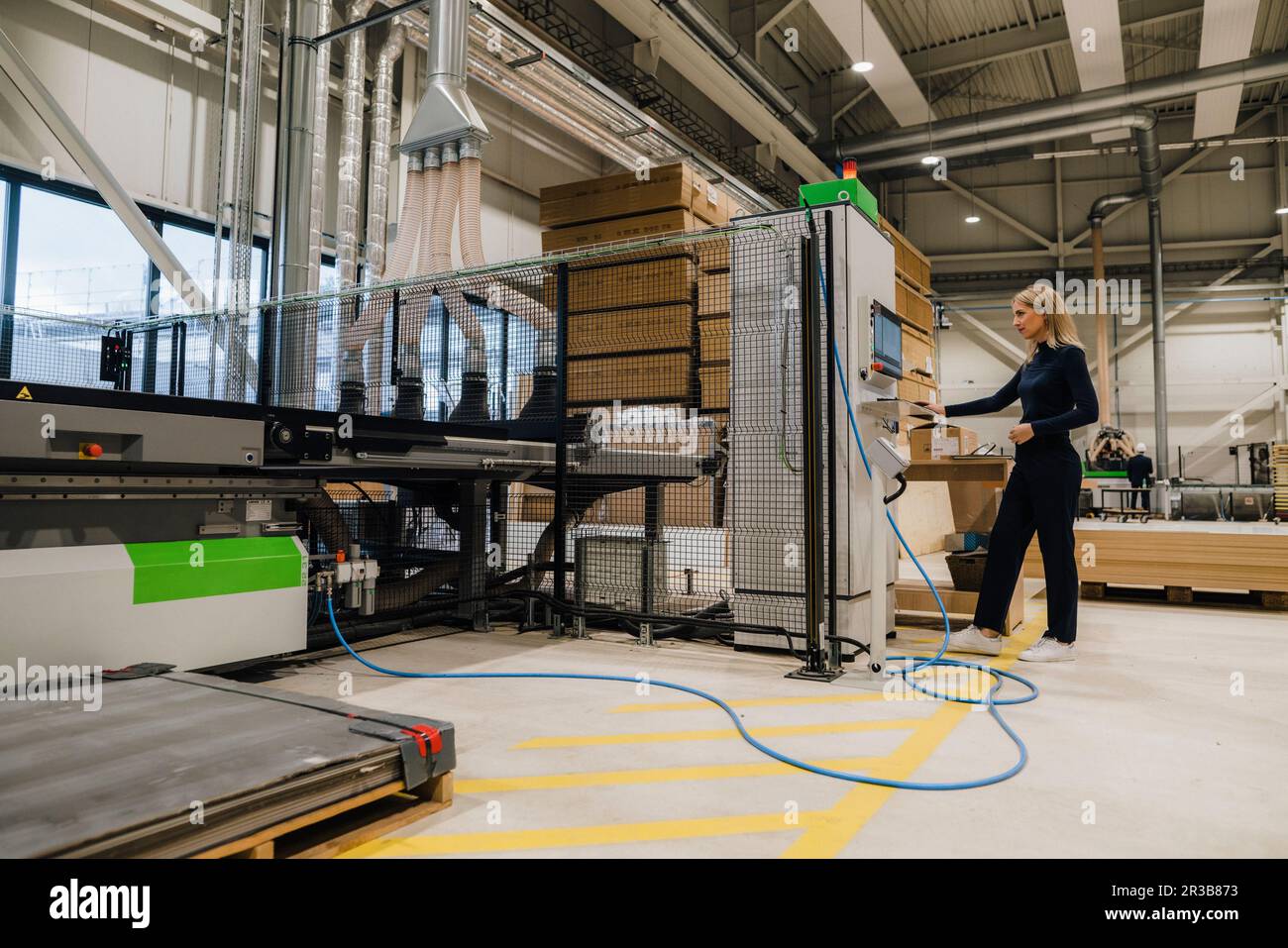 Femme d'affaires utilisant la machine dans l'usine de menuiserie Banque D'Images