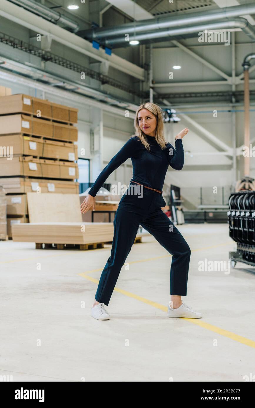 Femme d'affaires souriante dansant dans l'usine de menuiserie Banque D'Images