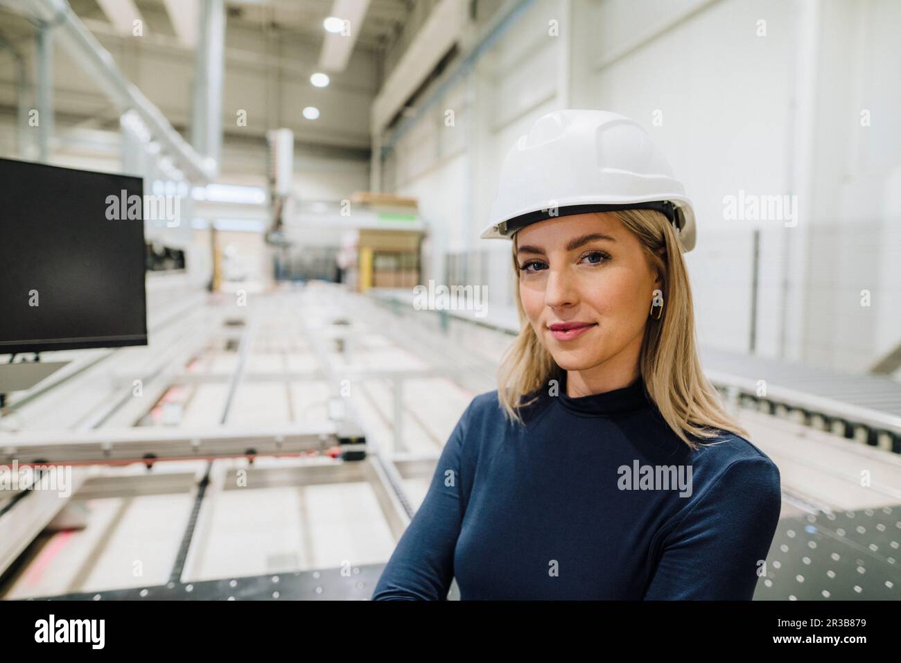 Femme d'affaires confiante portant un casque de sécurité dans l'usine de menuiserie Banque D'Images
