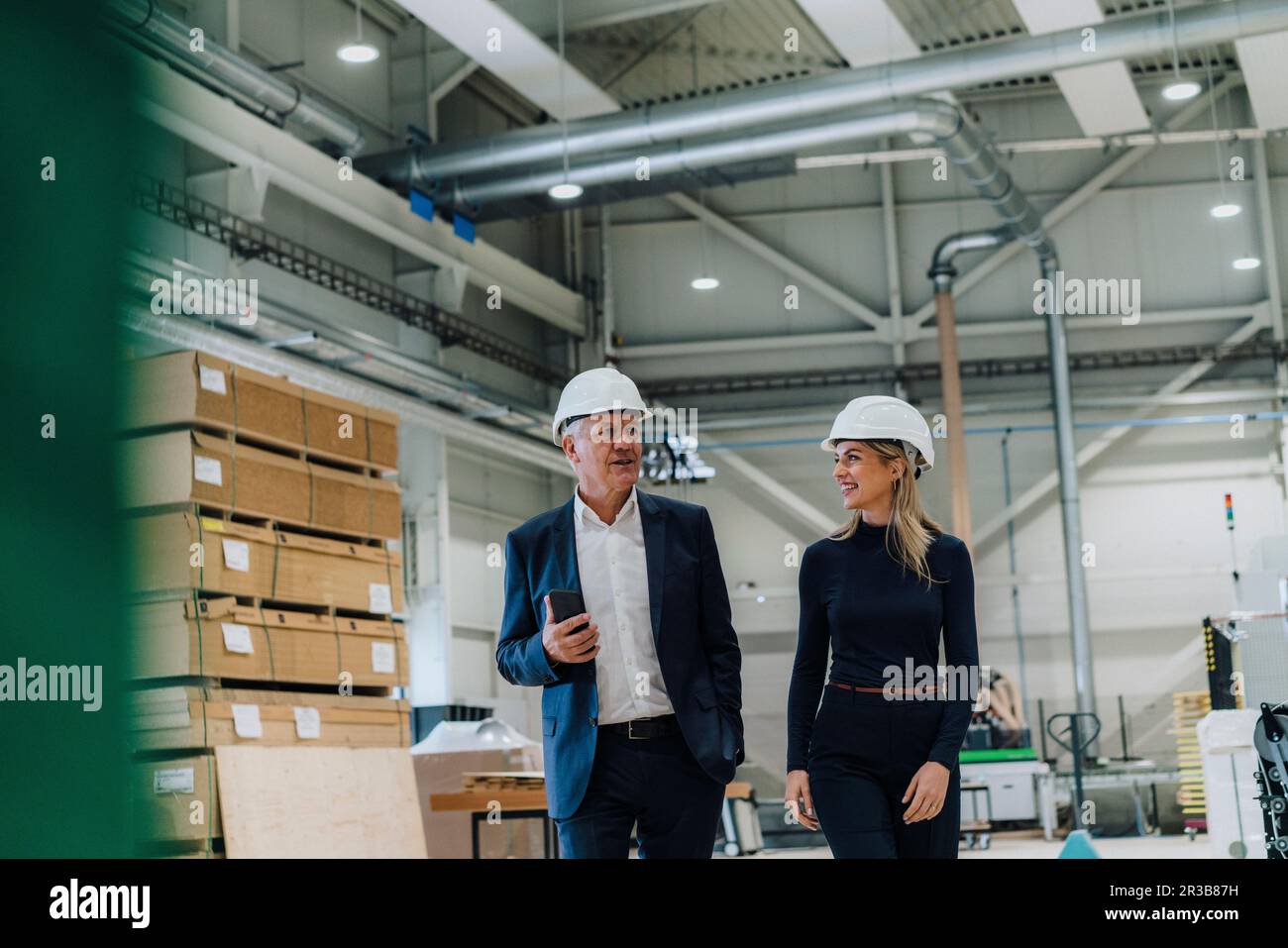 Homme d'affaires senior discutant avec un collègue souriant de l'usine de menuiserie Banque D'Images