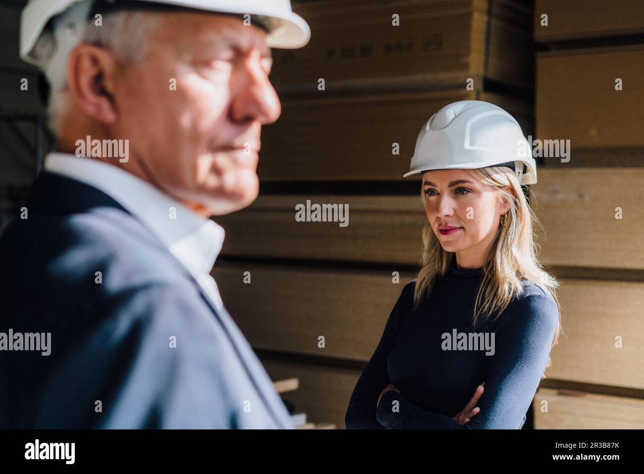 Femme d'affaires réfléchie portant un casque de sécurité dans l'usine de menuiserie Banque D'Images